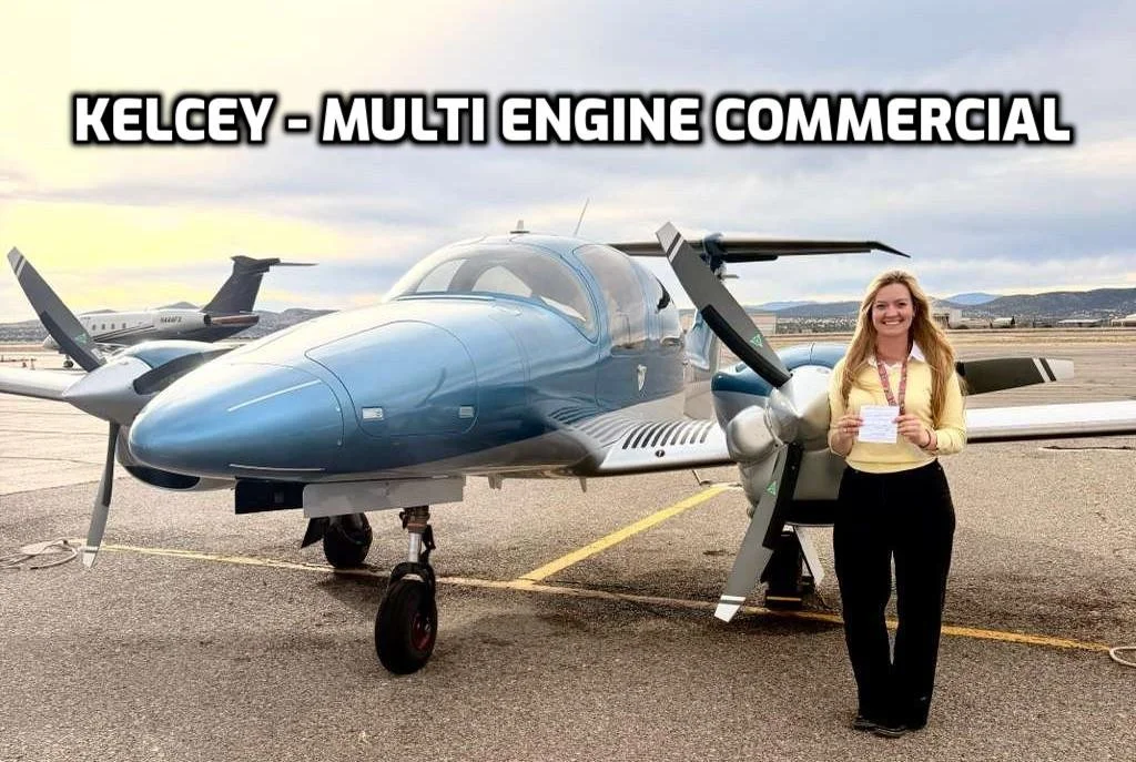 A woman standing in front of a blue multi-engine aircraft at an airport, holding a paper and smiling.
