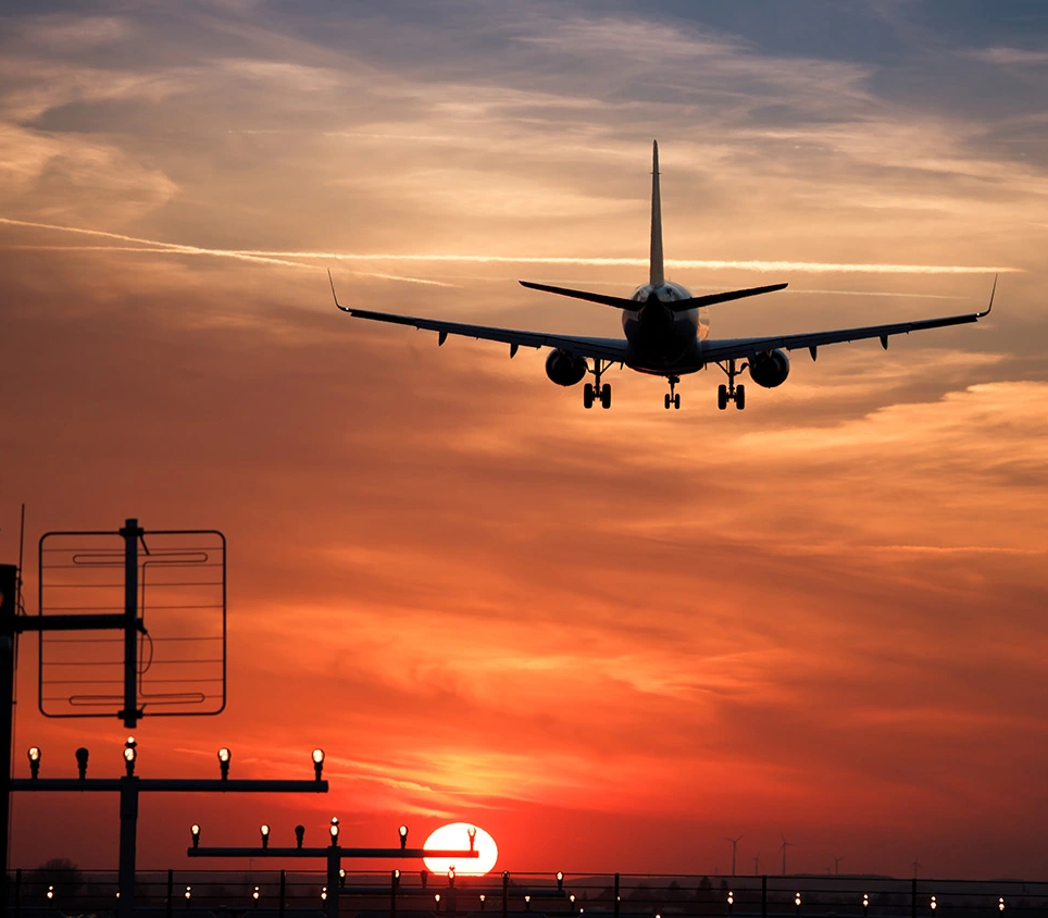 Airplane descending during sunset at an airport.