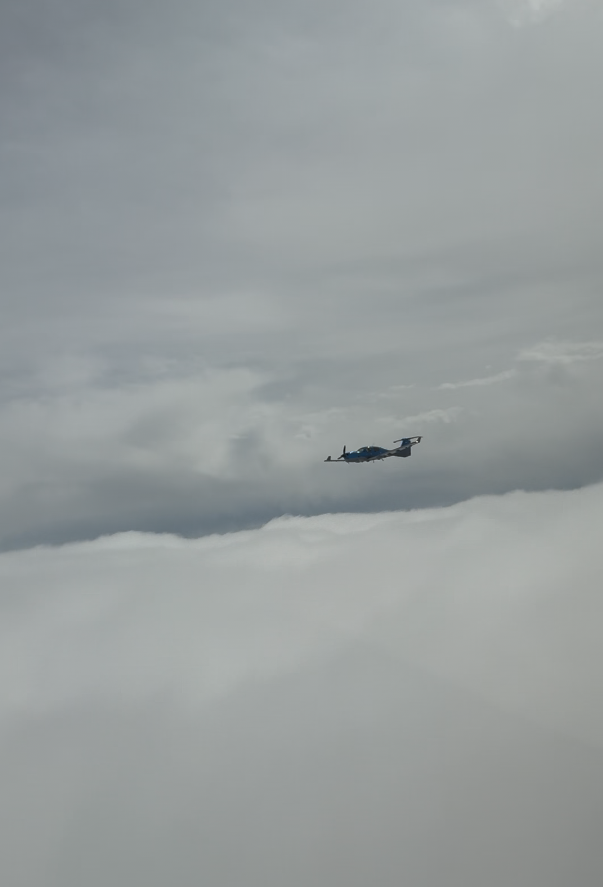 Military aircraft flying in cloudy sky.
