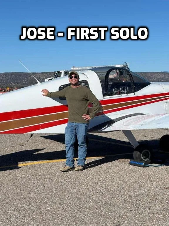 A man wearing sunglasses, a green sweater, and jeans standing in front of a small white airplane with red and gold stripes, touching the nose of the plane, with the text 'Jose - First Solo' at the top.