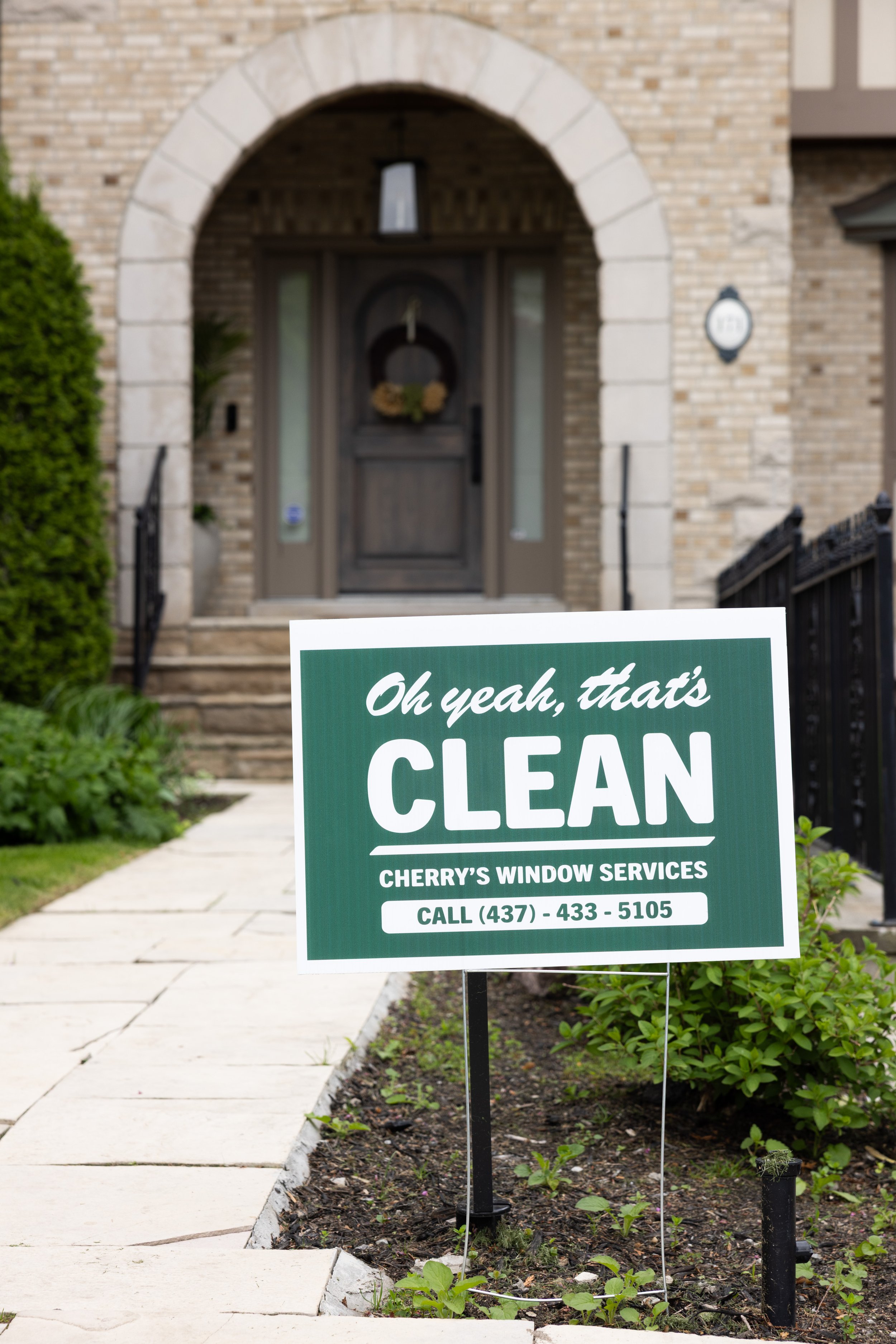 Sign in front of a house with a brick pathway and garden, advertising Cherry's Window Services with a phone number.