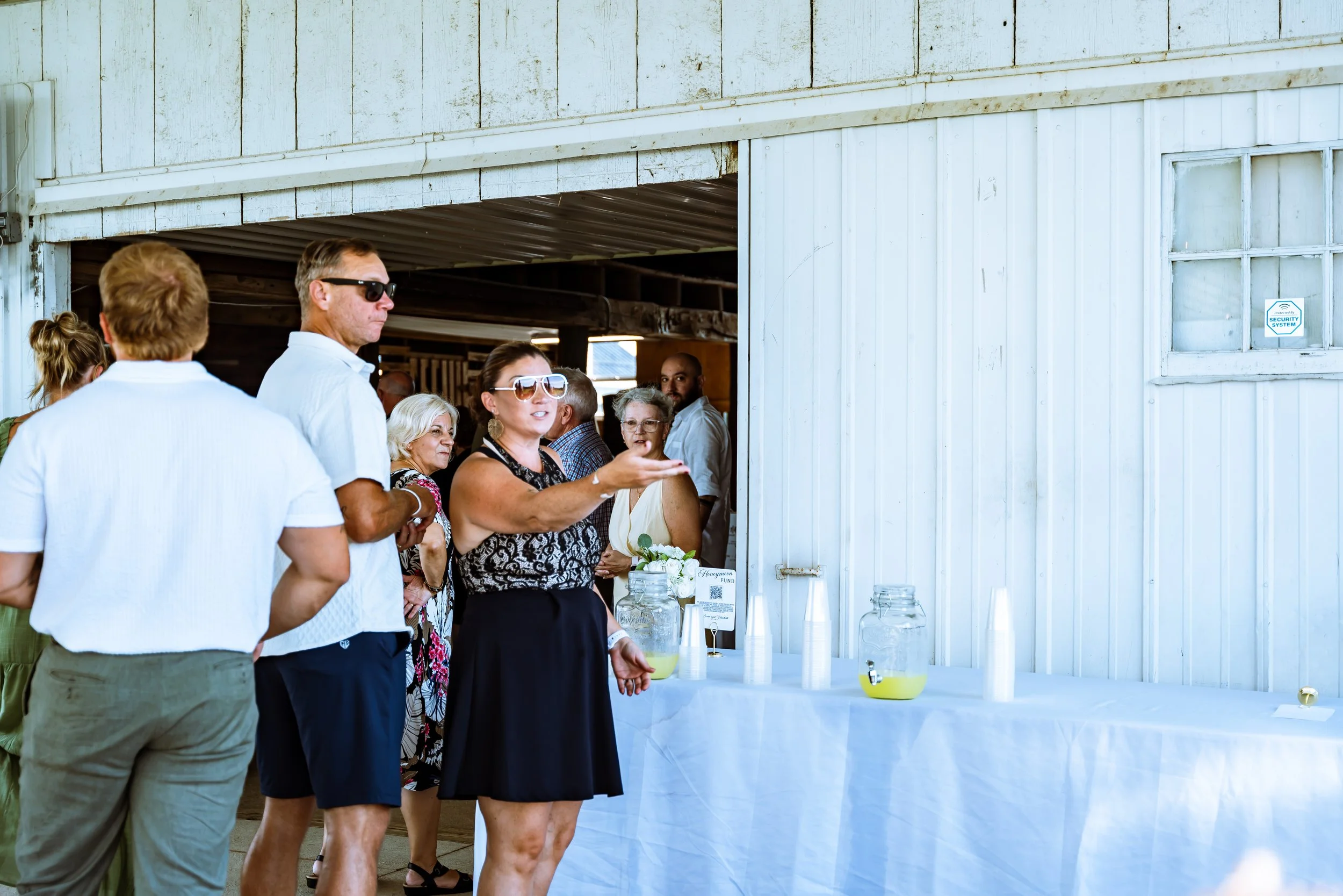 People standing in line at an outdoor event, with a white building in the background.