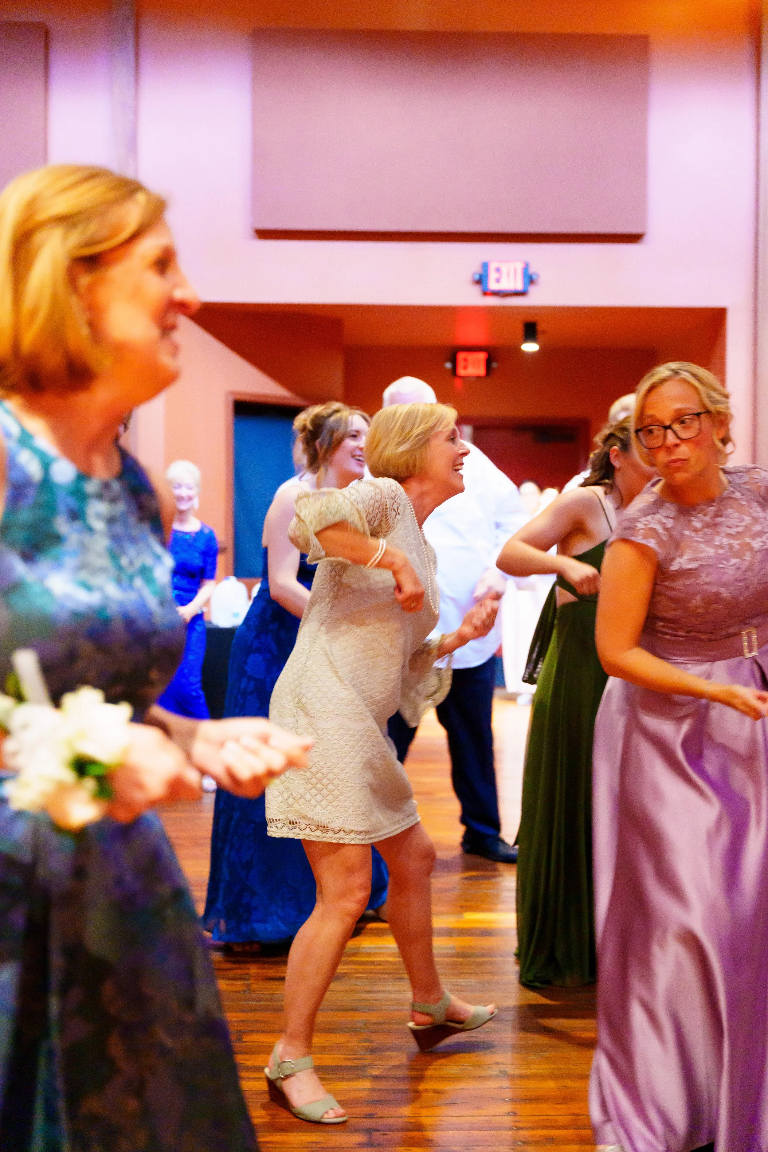 Group of women dancing and smiling at an indoor event.