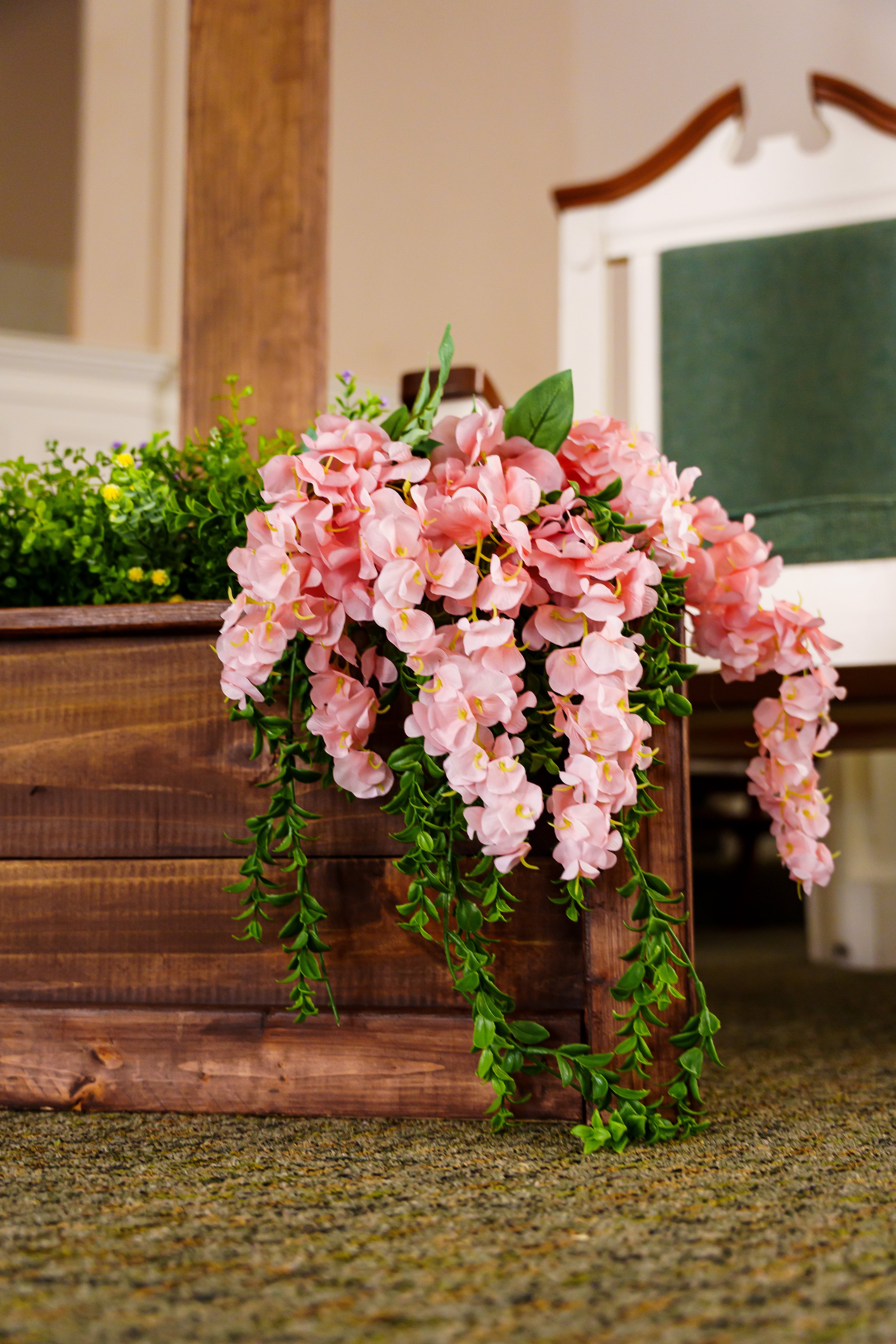 Pink and green artificial flower arrangement on a wooden flower box.