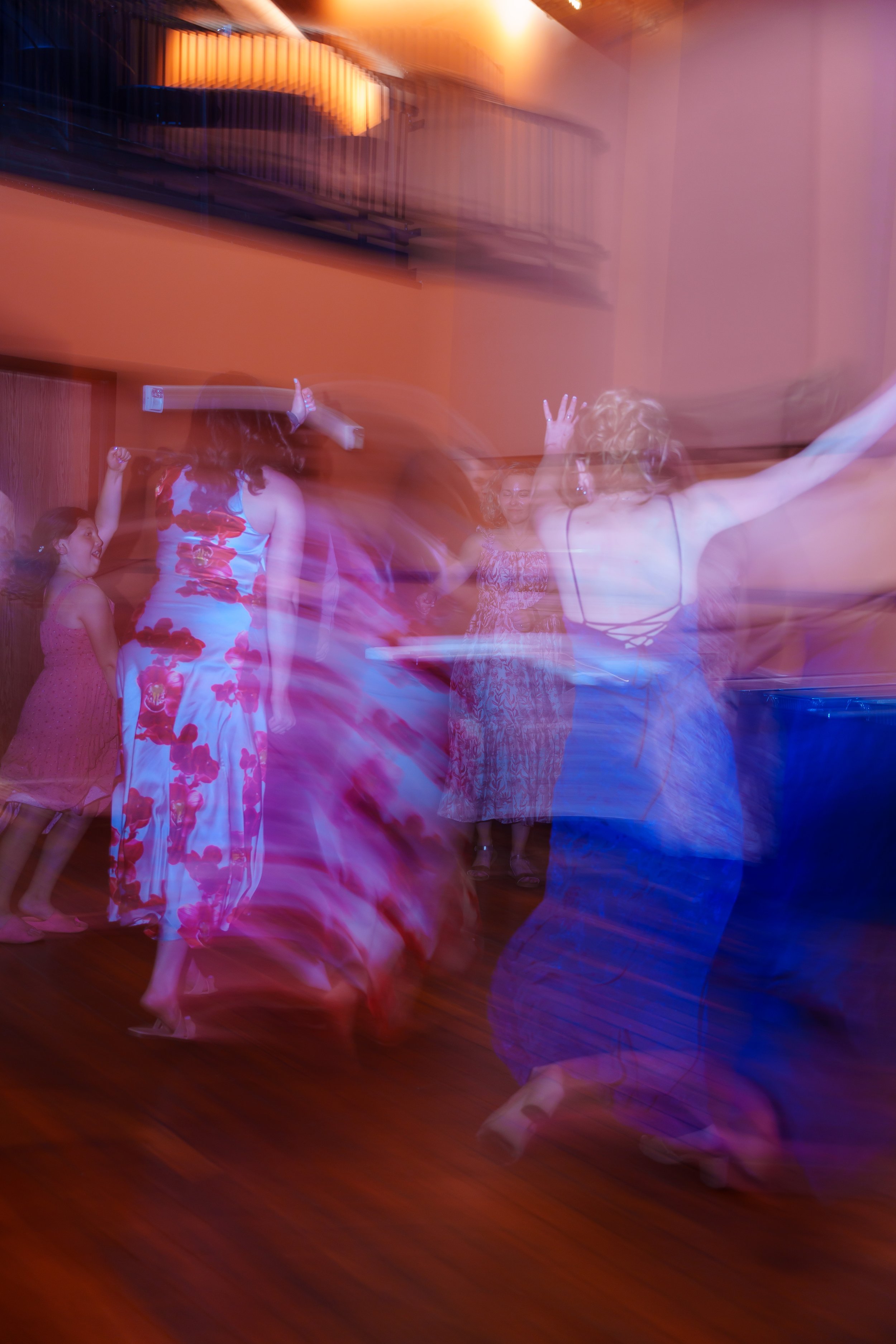 People dancing at a party, with blurred motion and colorful lighting creating a lively, dynamic atmosphere.