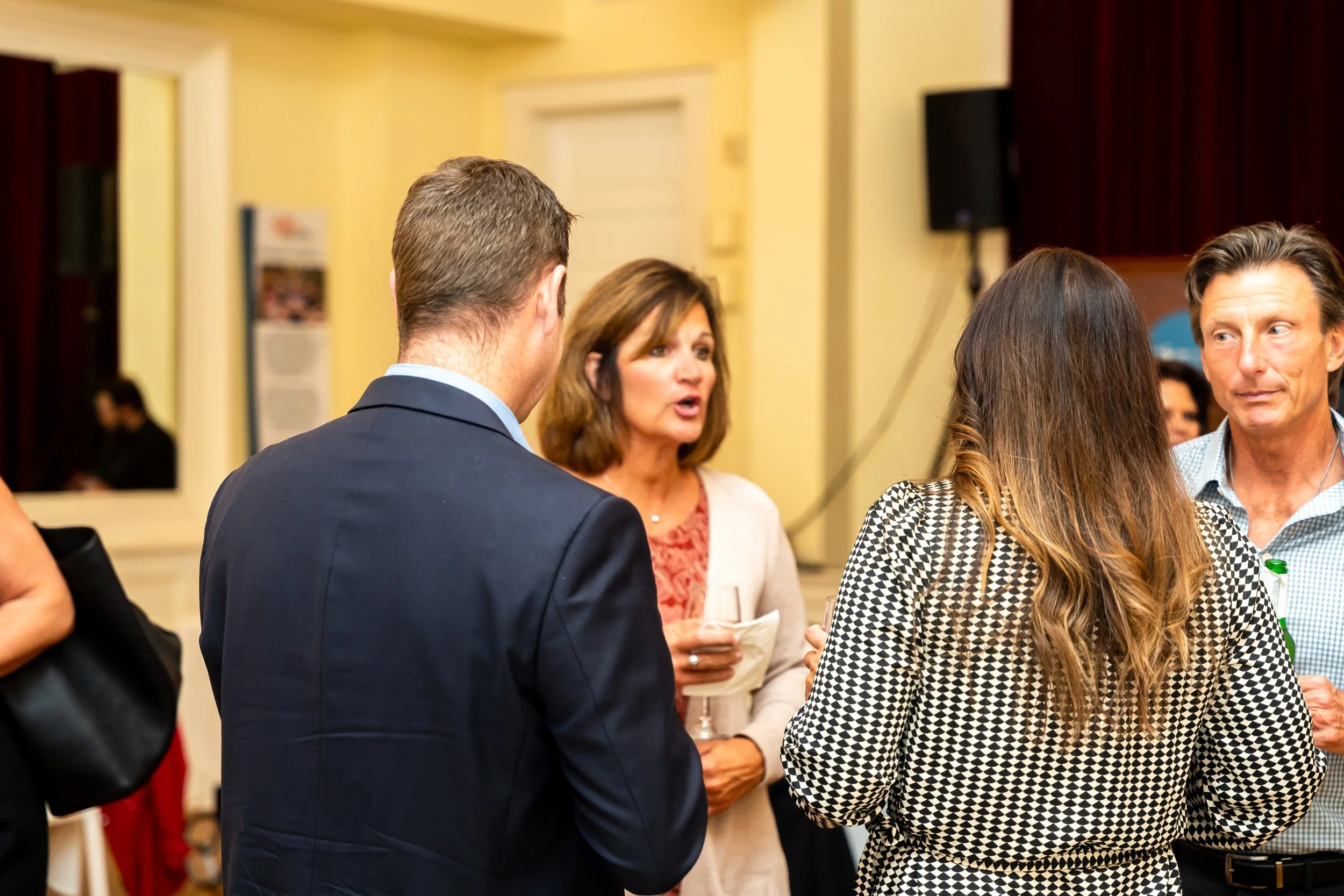 People engaged in conversation at a social event or gathering indoors.