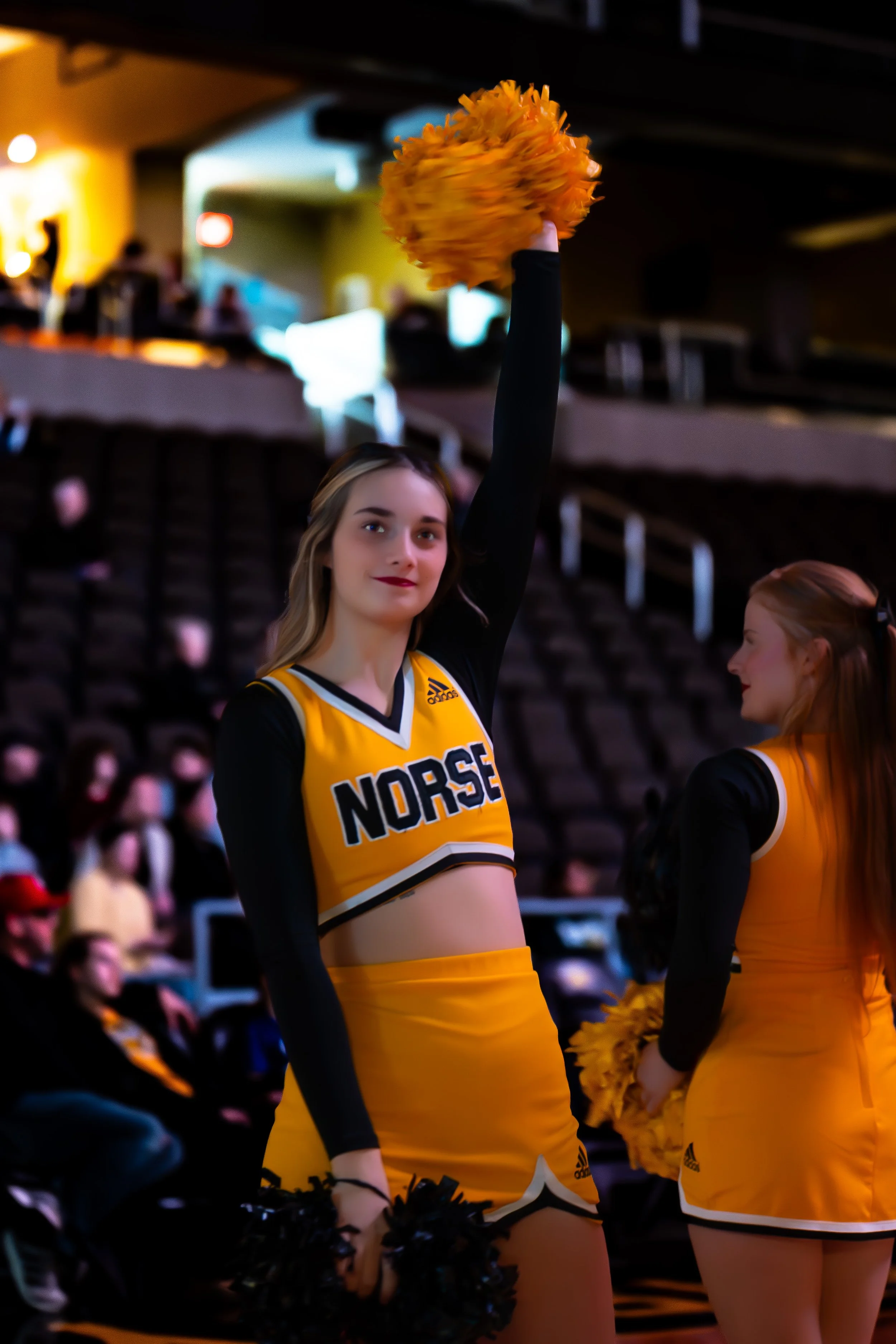 A young female cheerleader in a yellow and black cheerleading uniform with 