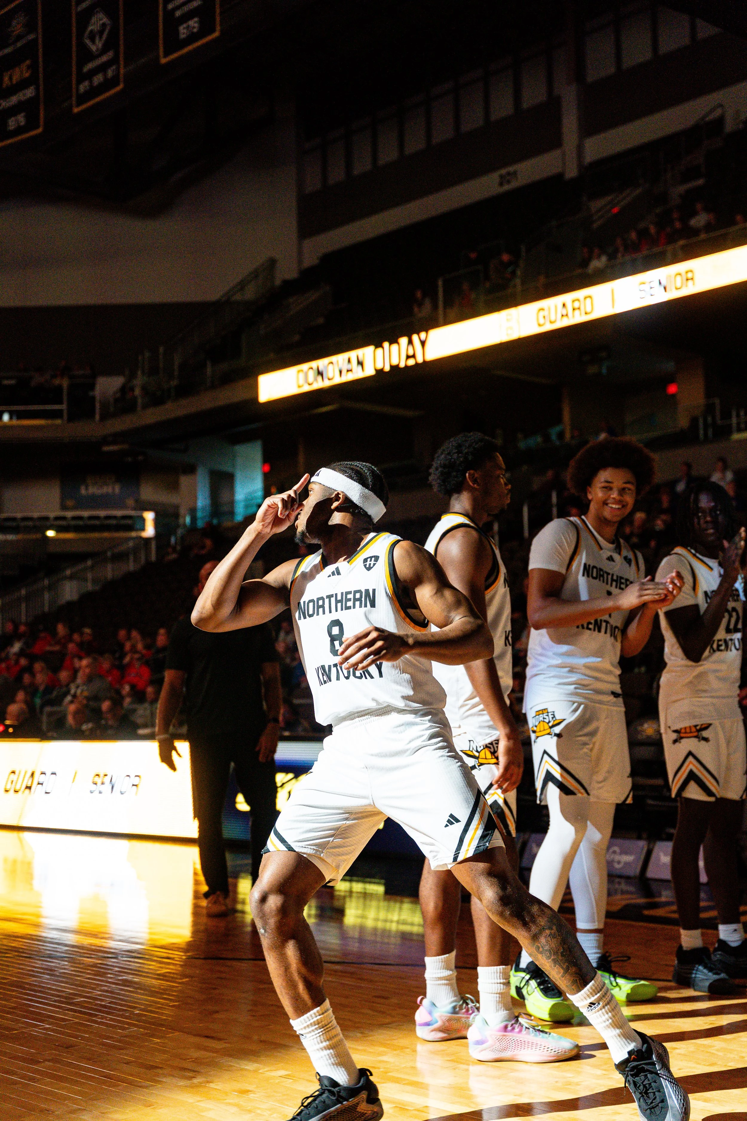 Basketball players from Northern Kentucky team on the court during a game, with some clapping and one player celebrating.