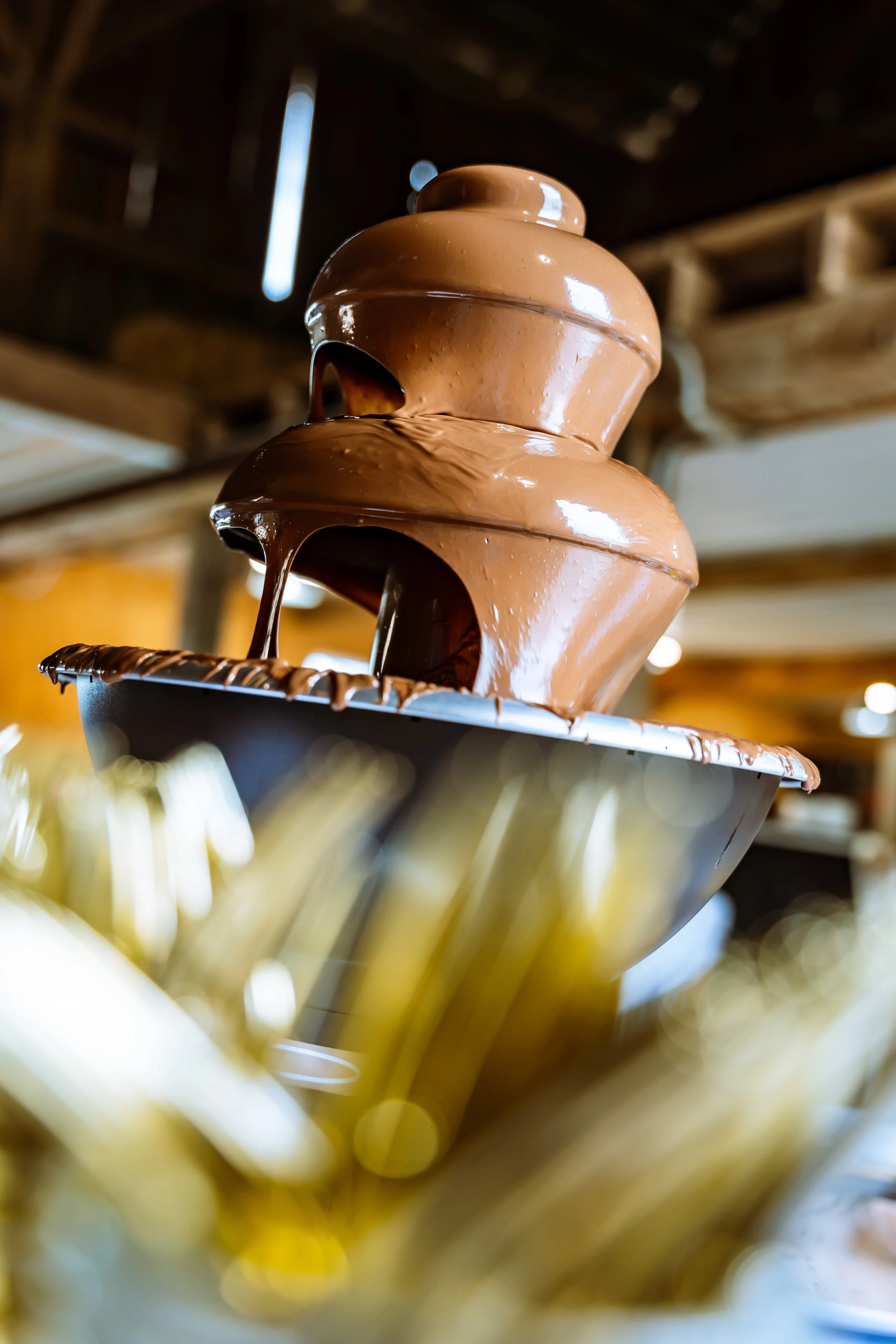Close-up of a chocolate fountain with flowing melted chocolate in tiers, set in a bakery or dessert shop.