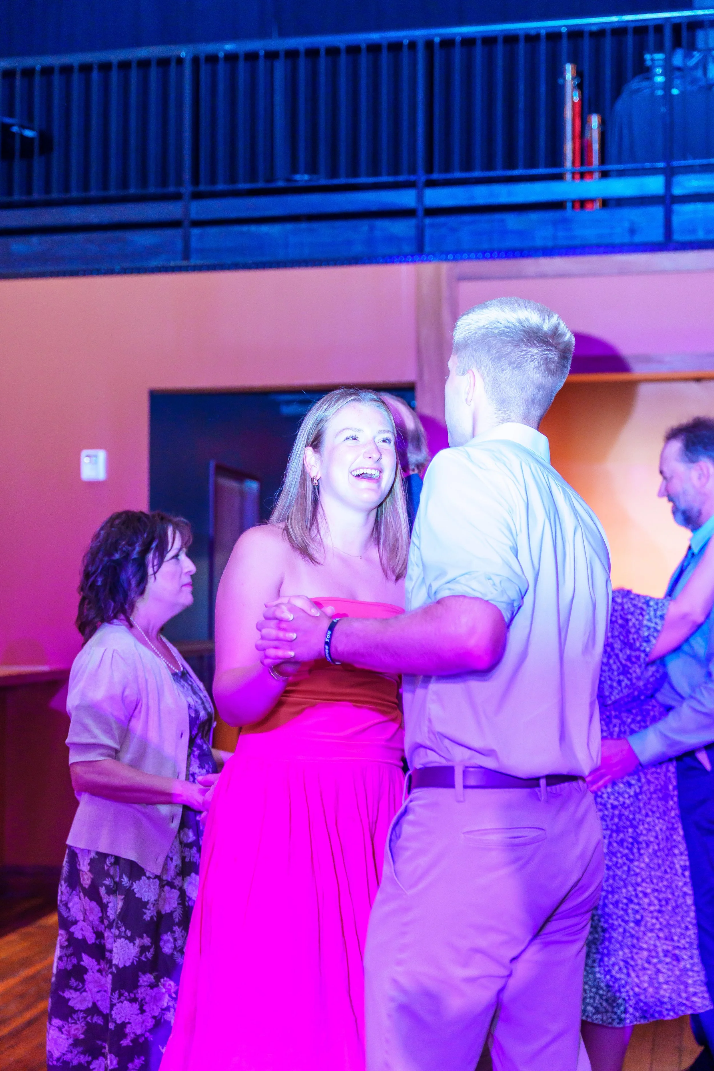 People dancing and socializing at a party or event with colorful lighting.
