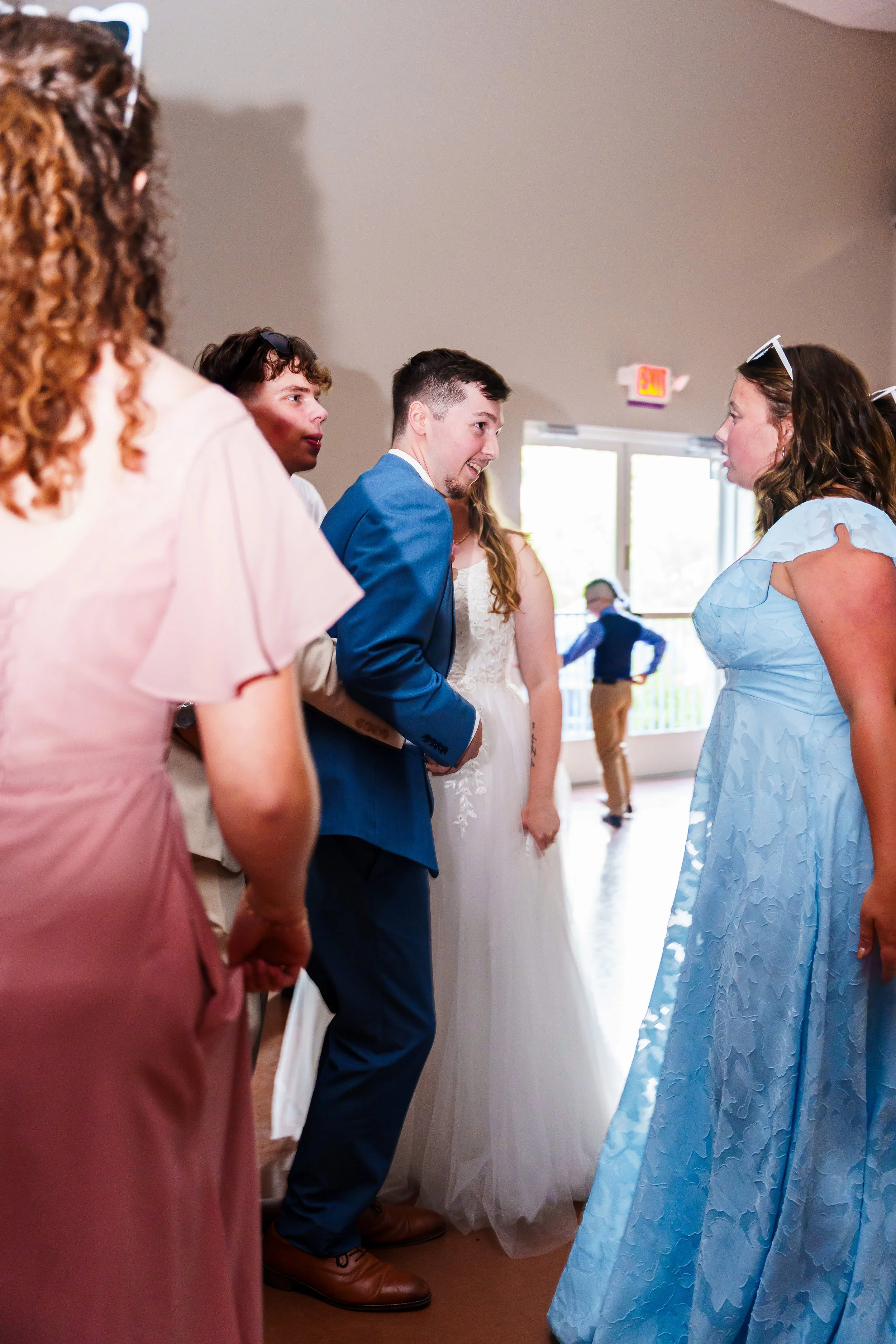 People dancing at a wedding reception, focusing on a woman in a blue dress and a man in a blue suit.
