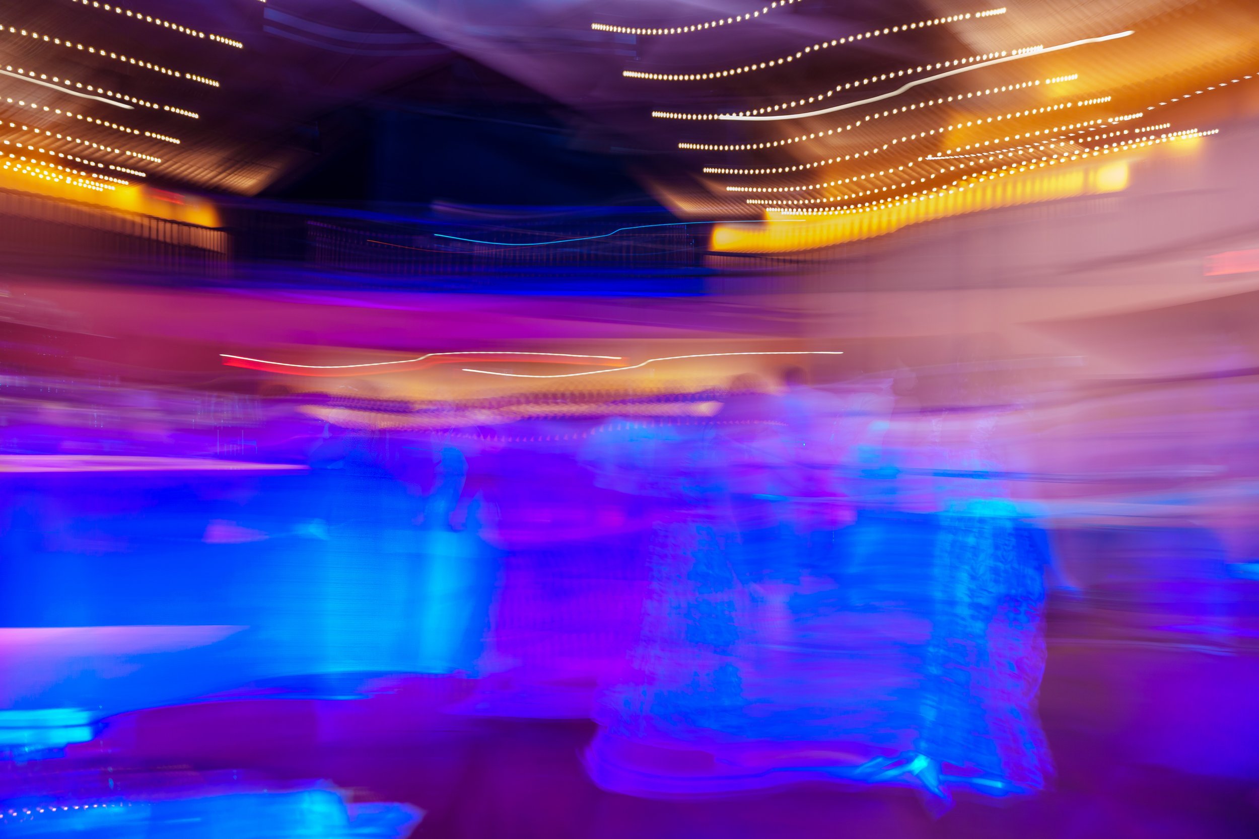 Colorful, abstract light trail art with streaks of purple, blue, orange, yellow, and white lights creating a sense of motion and energy.
