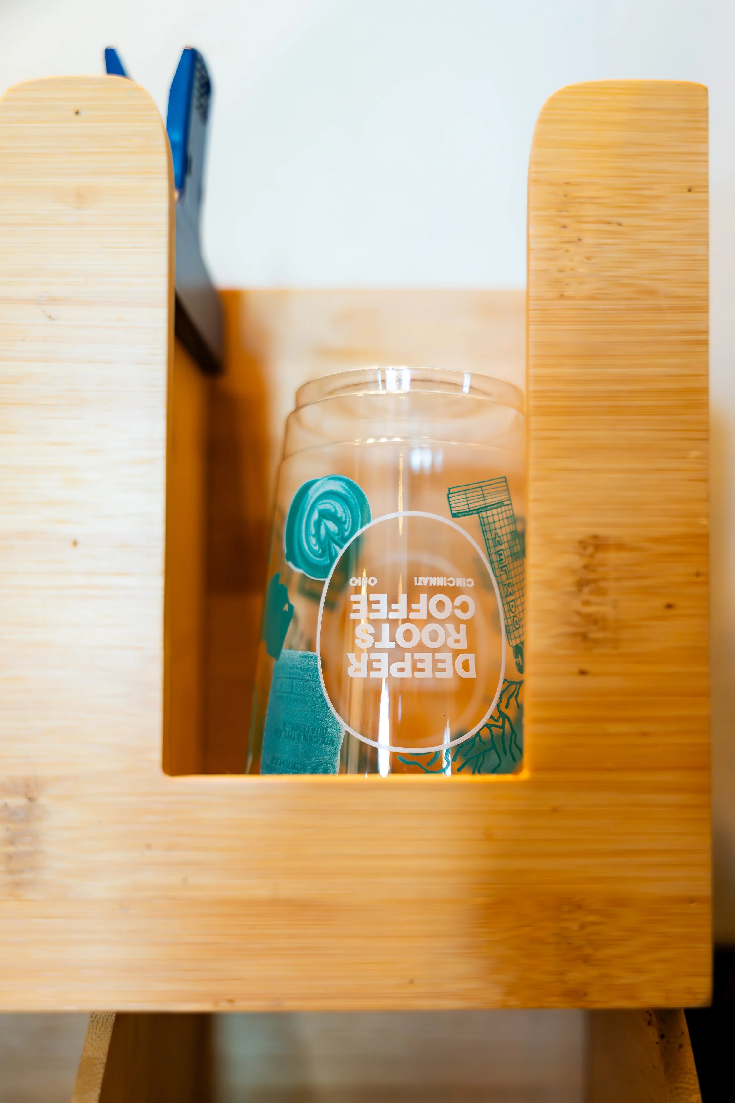 A wooden box with an oco logo on the front contains two clear plastic bottles of hand soap with blue pump tops, positioned on a light-colored wooden surface.