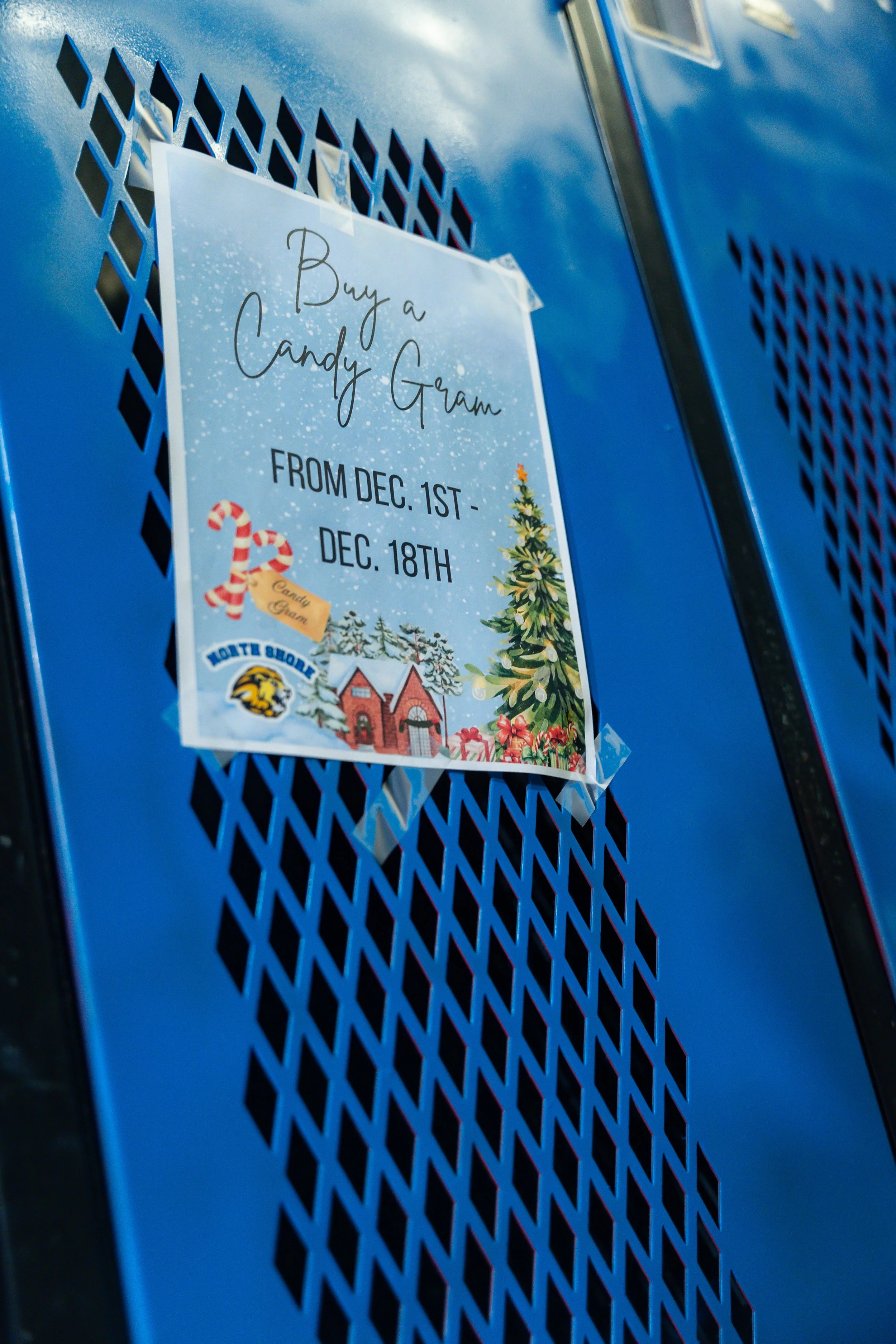 Blue school locker with a sign that reads 'Buy a Candy Gram' and dates from December 1st to December 18th, decorated with Christmas imagery including a Christmas tree, candy canes, and a house.