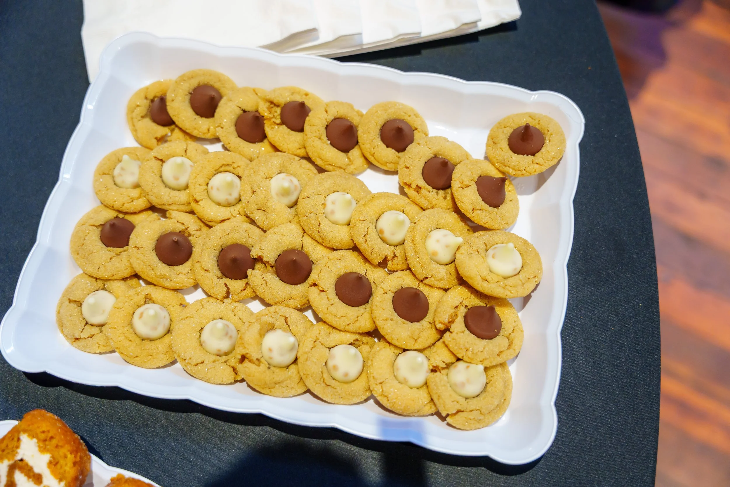 A white tray filled with cookies, some topped with white chocolate and others with milk chocolate.