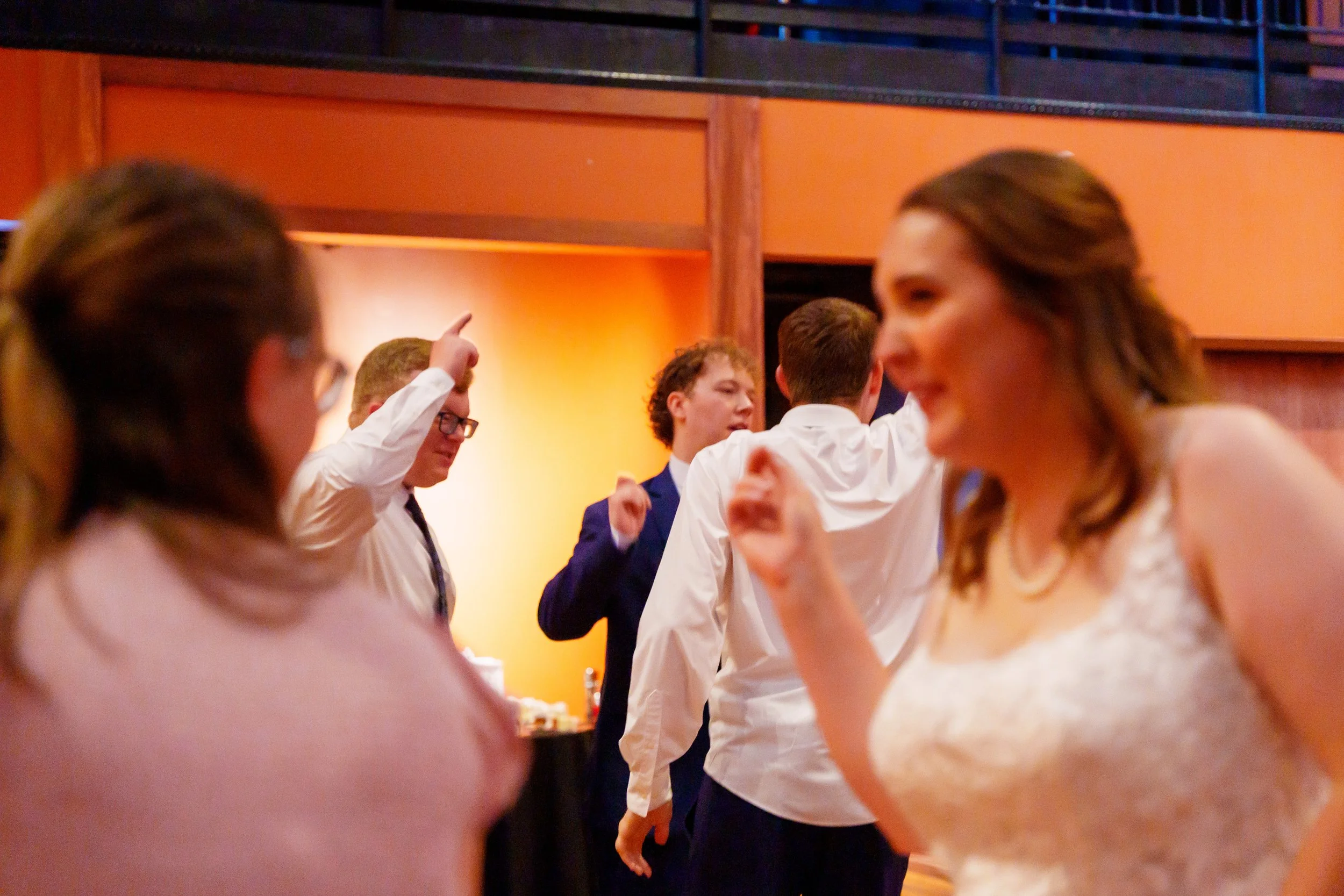 People dancing and socializing at a party in a warmly lit indoor space.