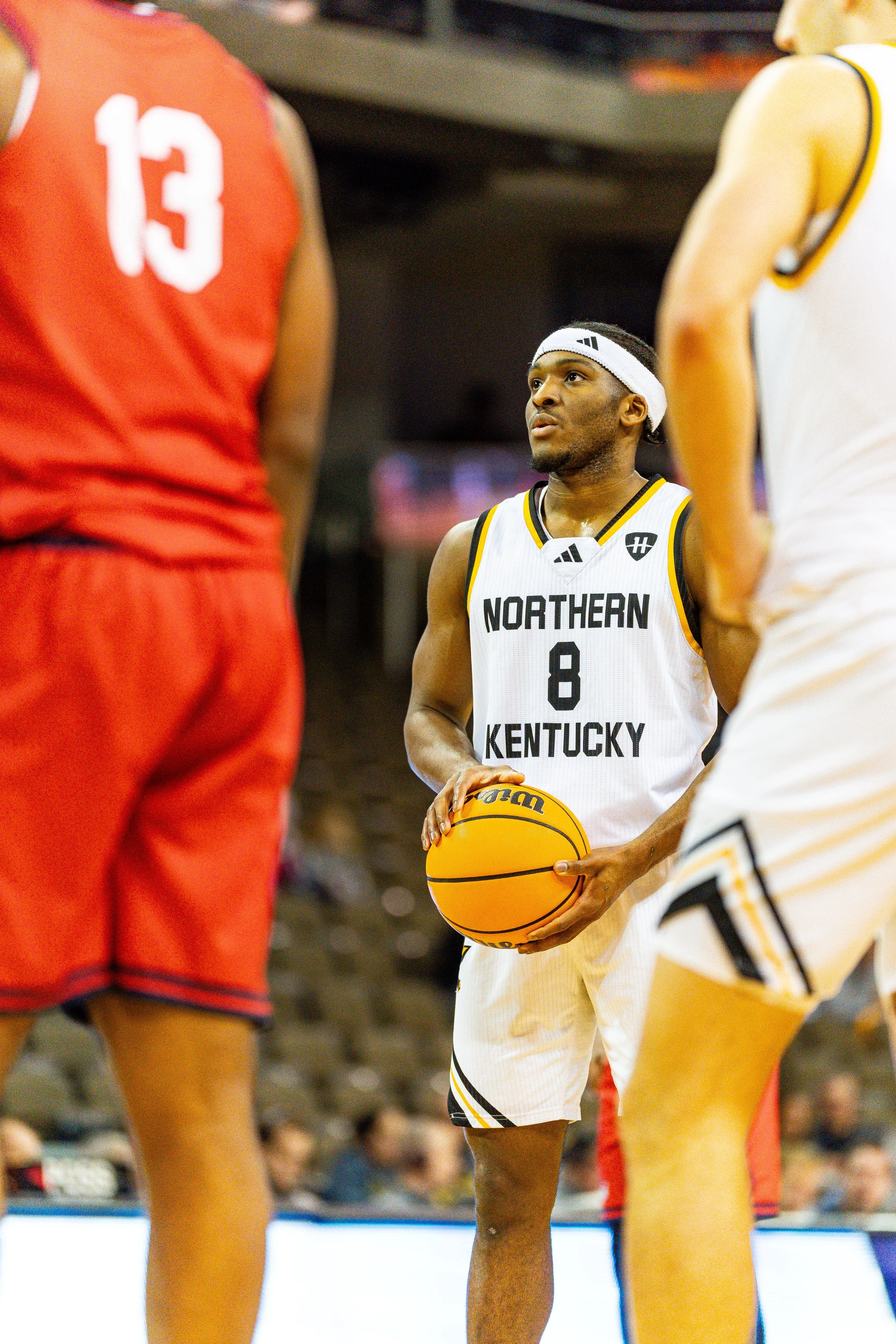 Basketball player from Northern Kentucky University holding a basketball during a game, surrounded by opponents.