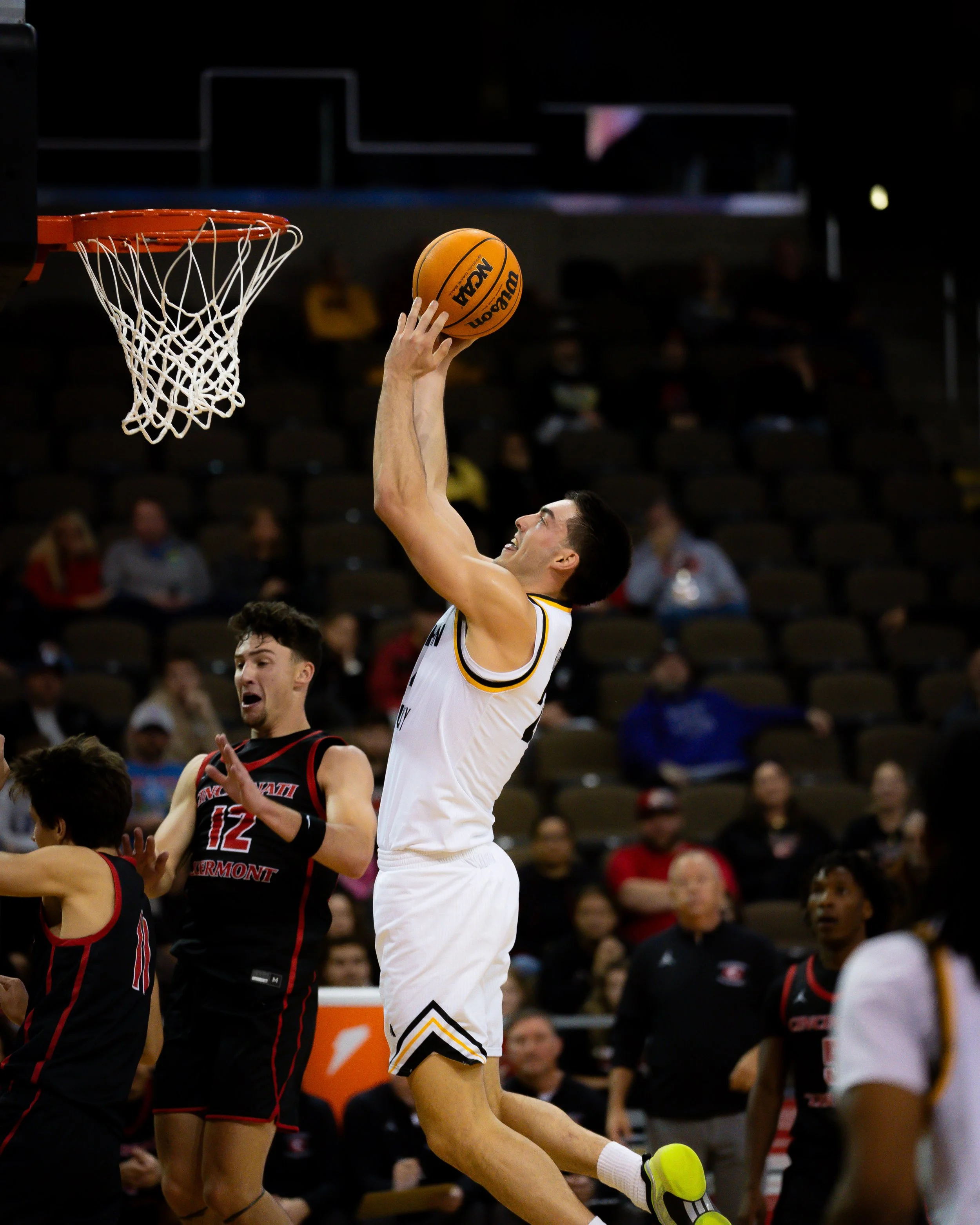 A basketball player in a white uniform is jumping towards the hoop, about to make a shot during a game.