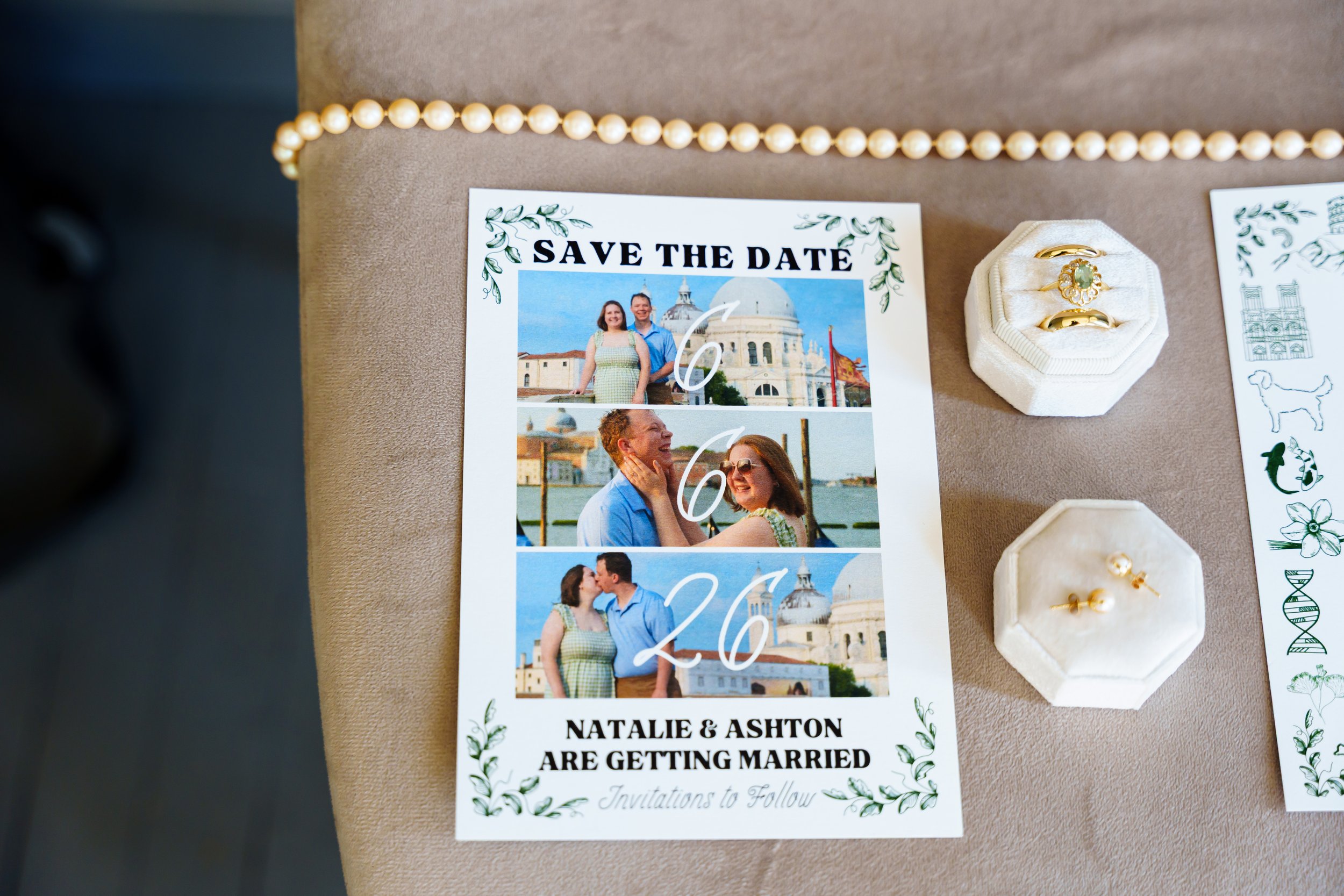 Wedding save the date card featuring photos of a couple outdoors with historic buildings in the background, surrounded by decorative greenery, with text announcing their wedding and names, Natalie and Ashton, with rings displayed nearby.