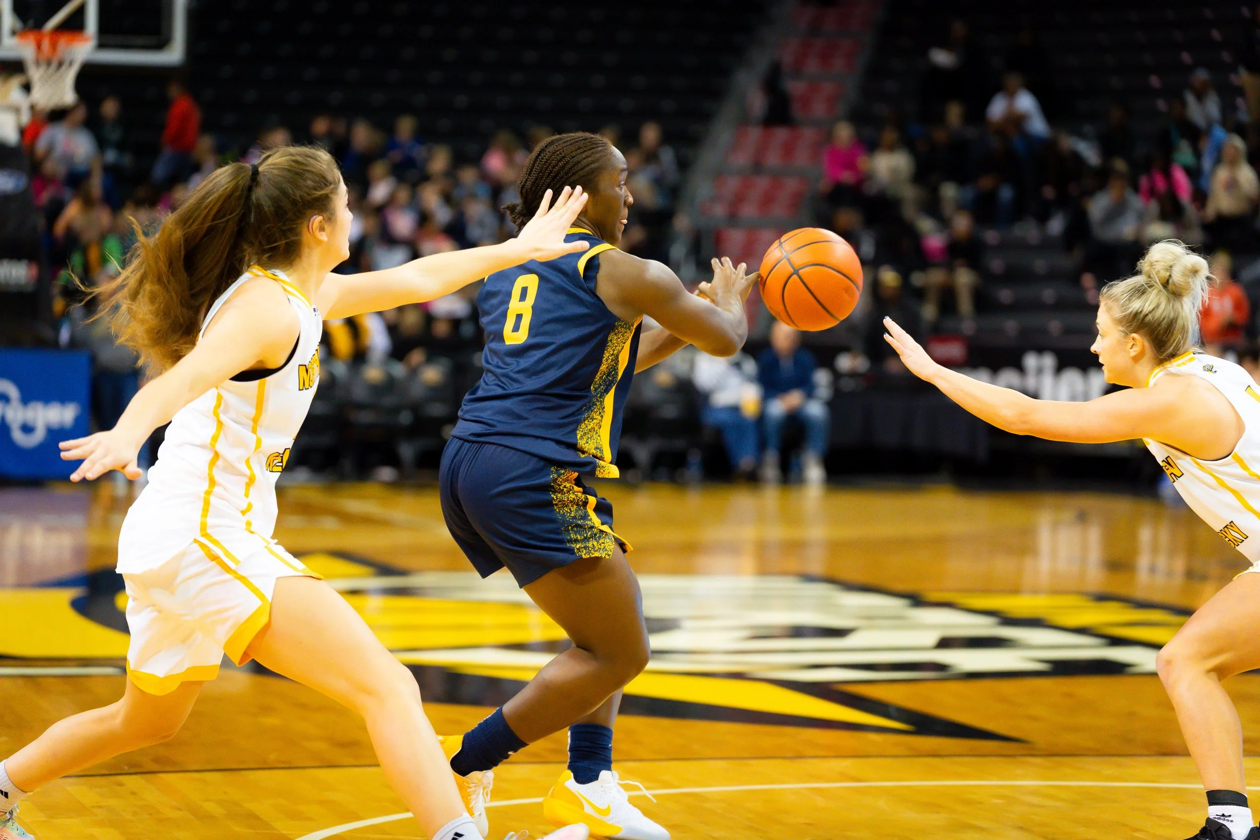 Women basketball players in action during a game, with one player holding the basketball and others reaching for it.