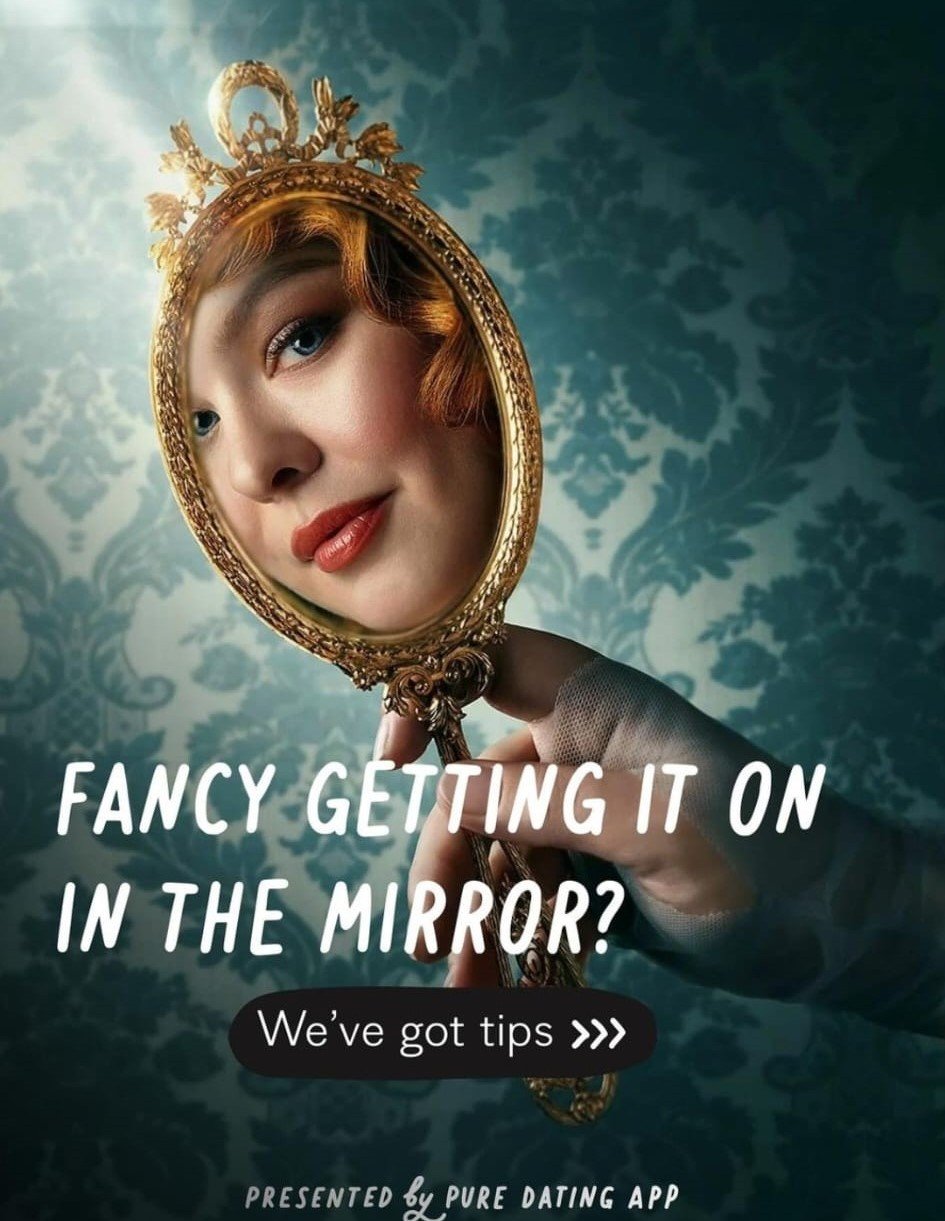 A woman with red hair and makeup holding a vintage hand mirror with a gold ornate frame, reflecting her face. The background features a blue patterned wallpaper. Text overlays say, "Fancy getting it on in the mirror?" and "We've got tips."