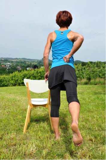 Selbsthilfe-Übung für den unteren Rücken: Mit einem Bein schwingen und währenddessen auf der gleichen Körperseite mit der Faust sanft am Kreuzbein drücken.