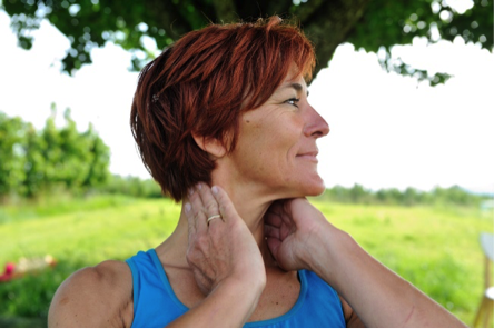 Selbsthilfe-Übung bei Nackenbeschwerden. Die Fingerspitzen drücken sanft gegen die seitlichen Fortsätze der Halswirbel, während der Kopf sich wie bei einer "Nein"-Bewegung dreht.