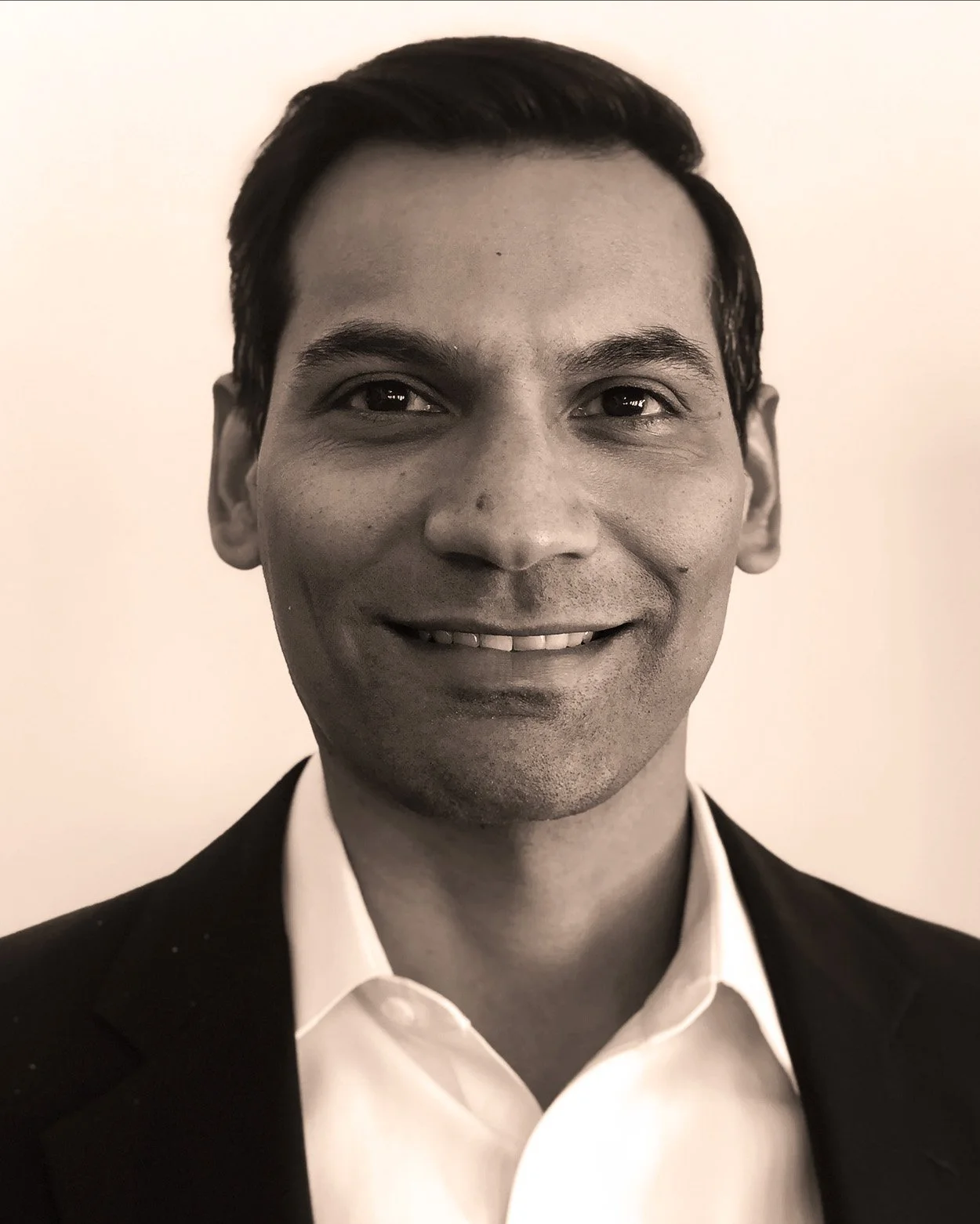 Black and white portrait of a smiling man wearing a suit and white shirt.