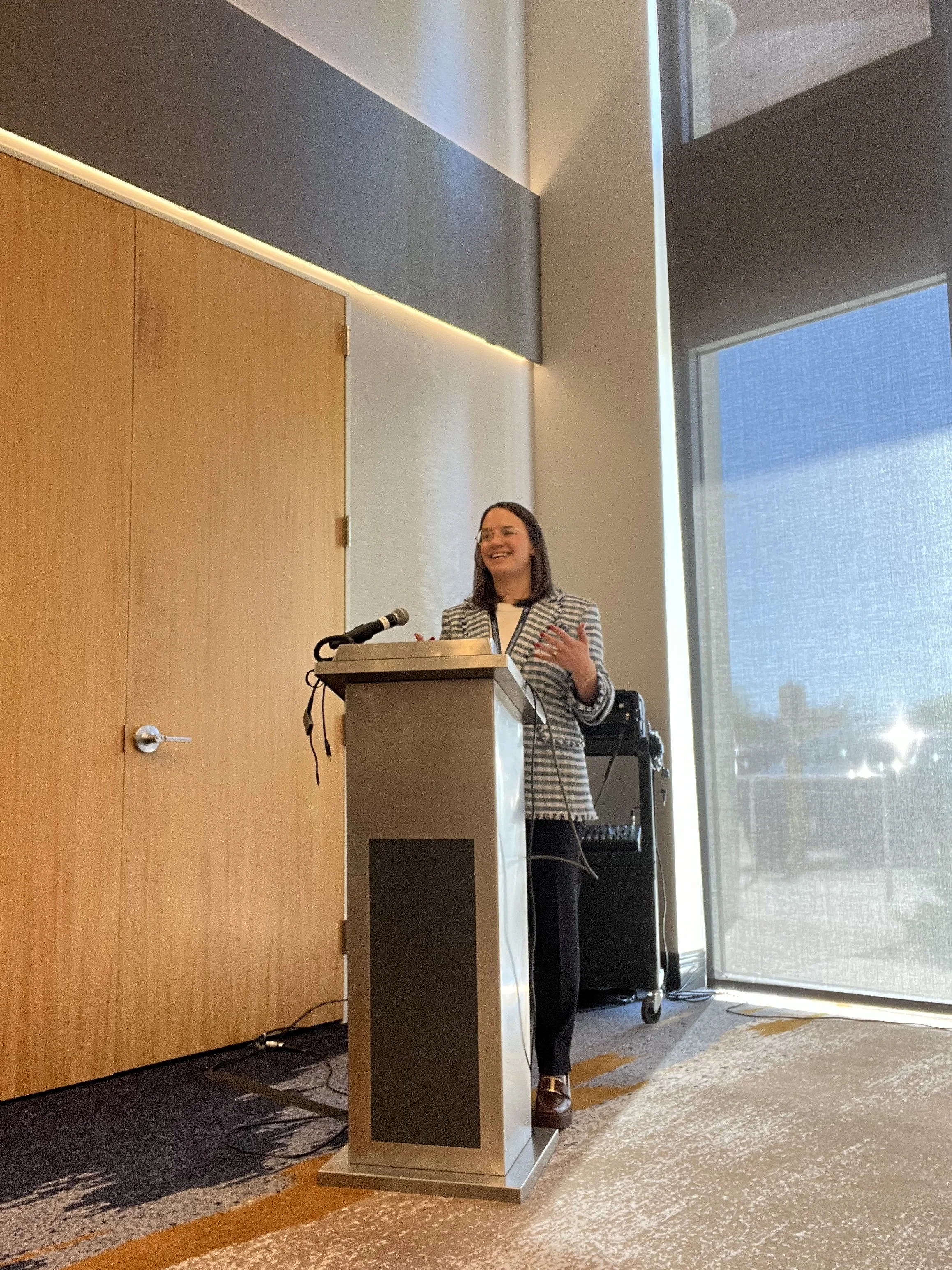 a white woman standing behind a podium speaking to an audience