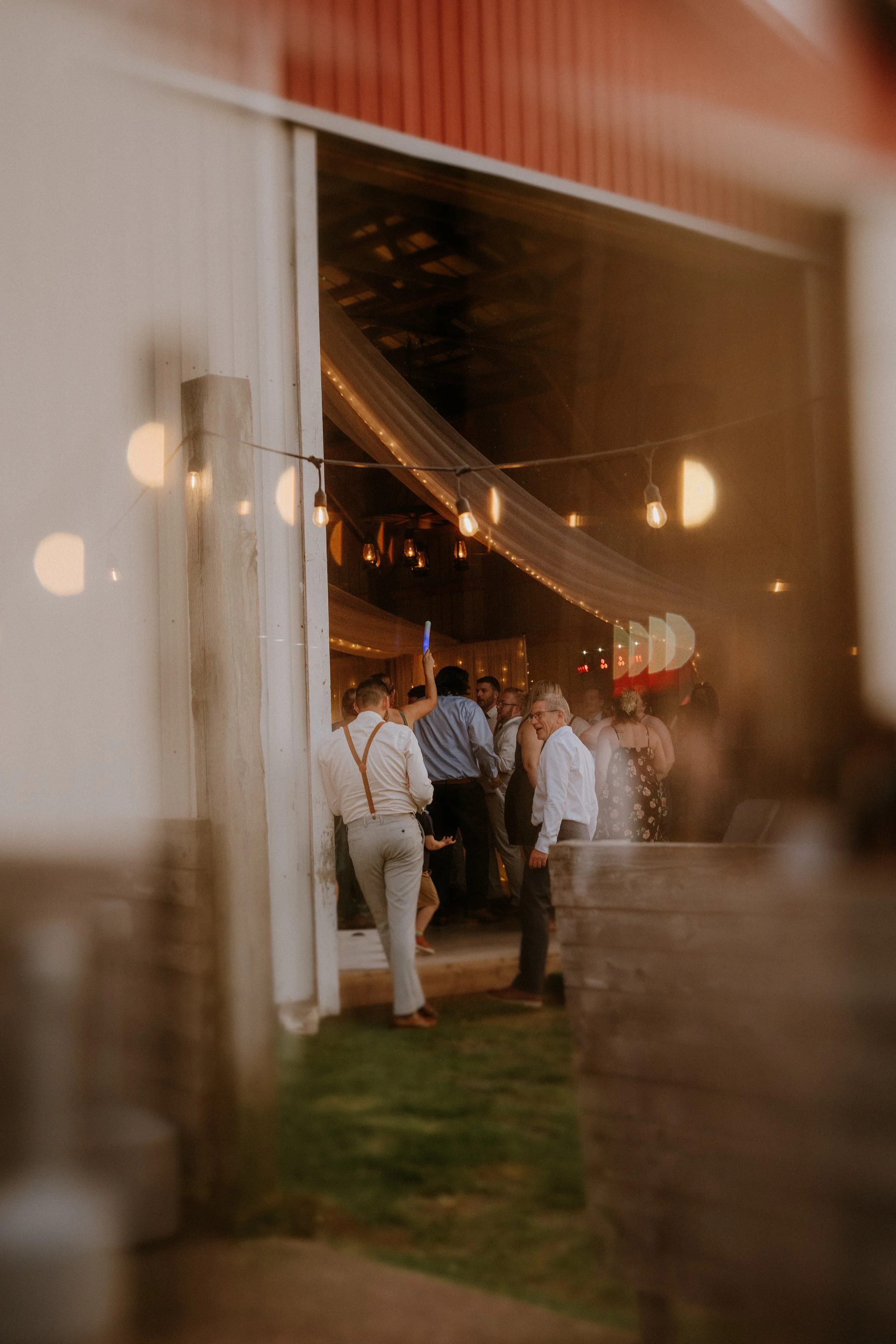 People dancing and socializing inside a decorated venue seen through an open door at night.