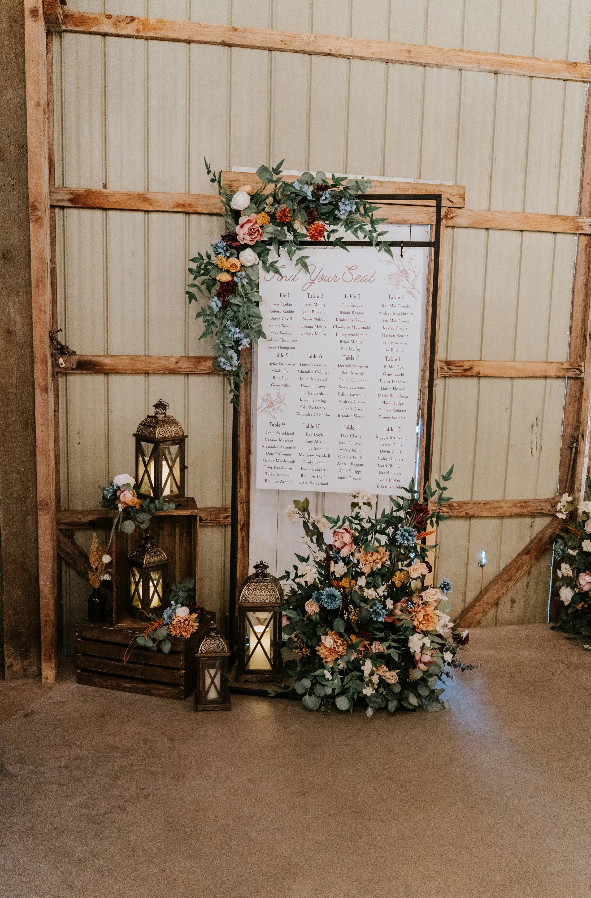 Wedding seating chart with floral decorations and lanterns.