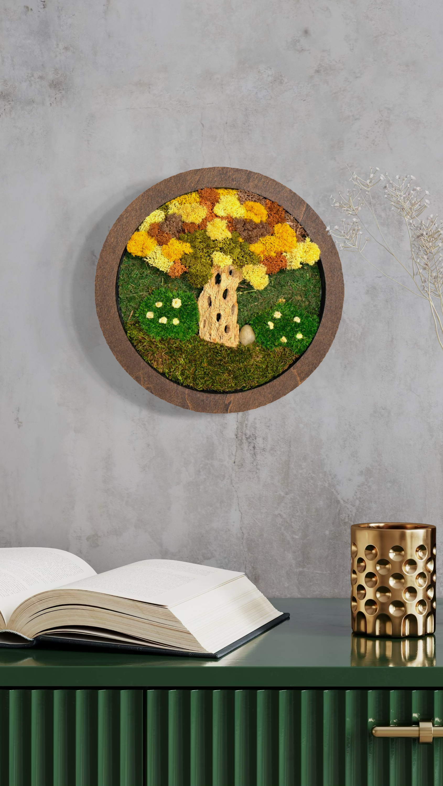 Decorative wall art with a circular frame containing a built-in tree design made of moss and flowers, mounted on a concrete wall.