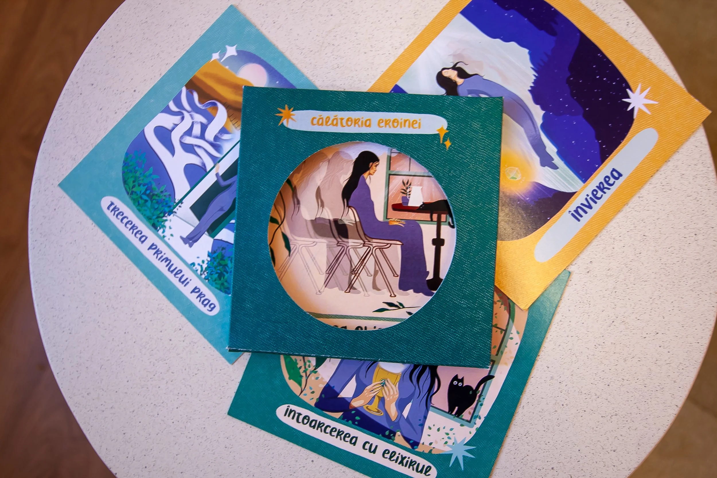 Colorful illustrated postcards and a card featuring a girl sitting at a desk with a tablet and a window. The postcards show various scenes, including mountains, stars, and a night sky, with some text in Romanian. - Carduri Calatoria Eroinei