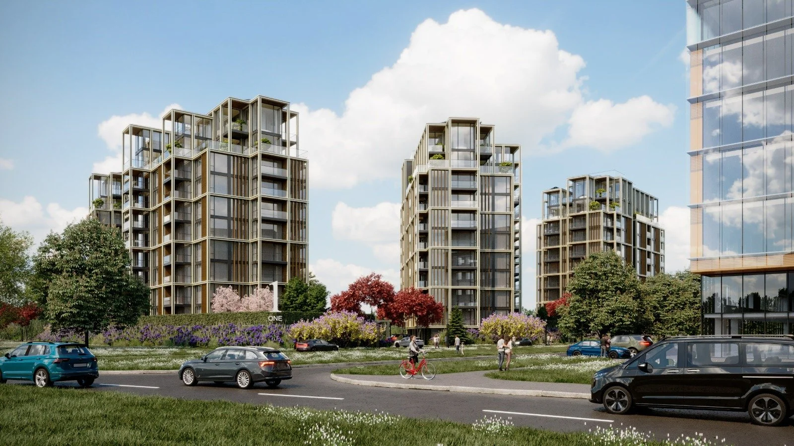 Modern residential complex with three tall, multi-story buildings, surrounded by greenery and parked cars, under a blue sky with clouds.