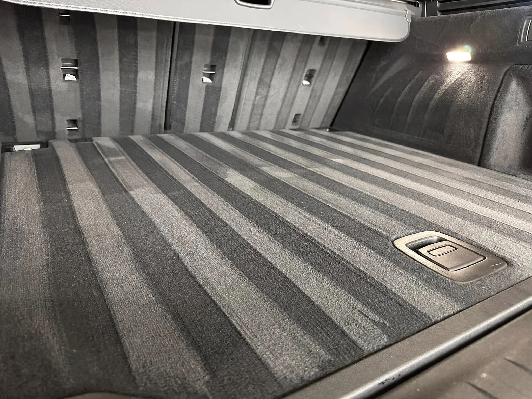 The interior cargo space of a vehicle with a striped gray mat covering the floor.