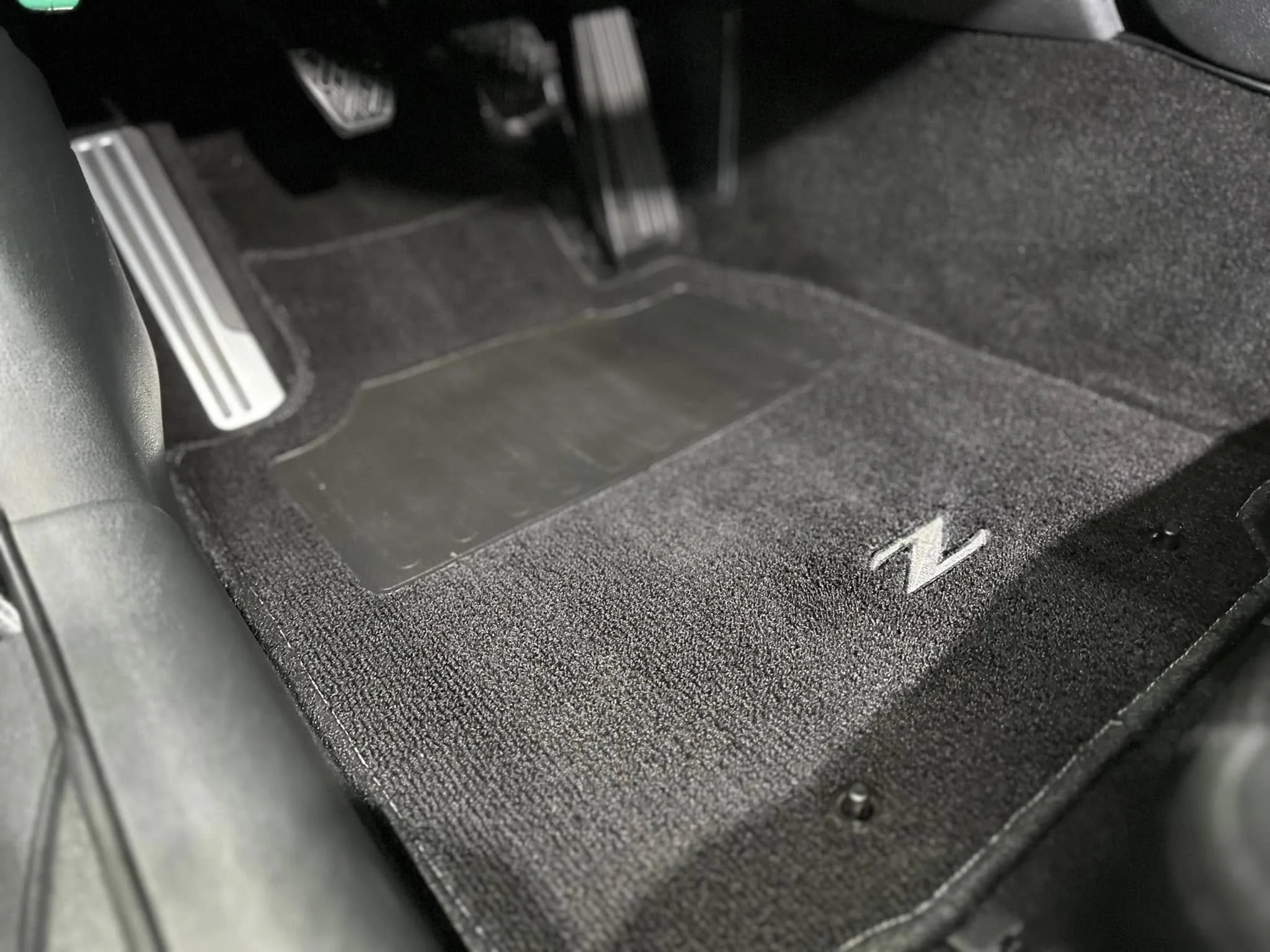 Inside view of a car's driver side floor mat with a gray embroidered letter 'Z' on the right side.