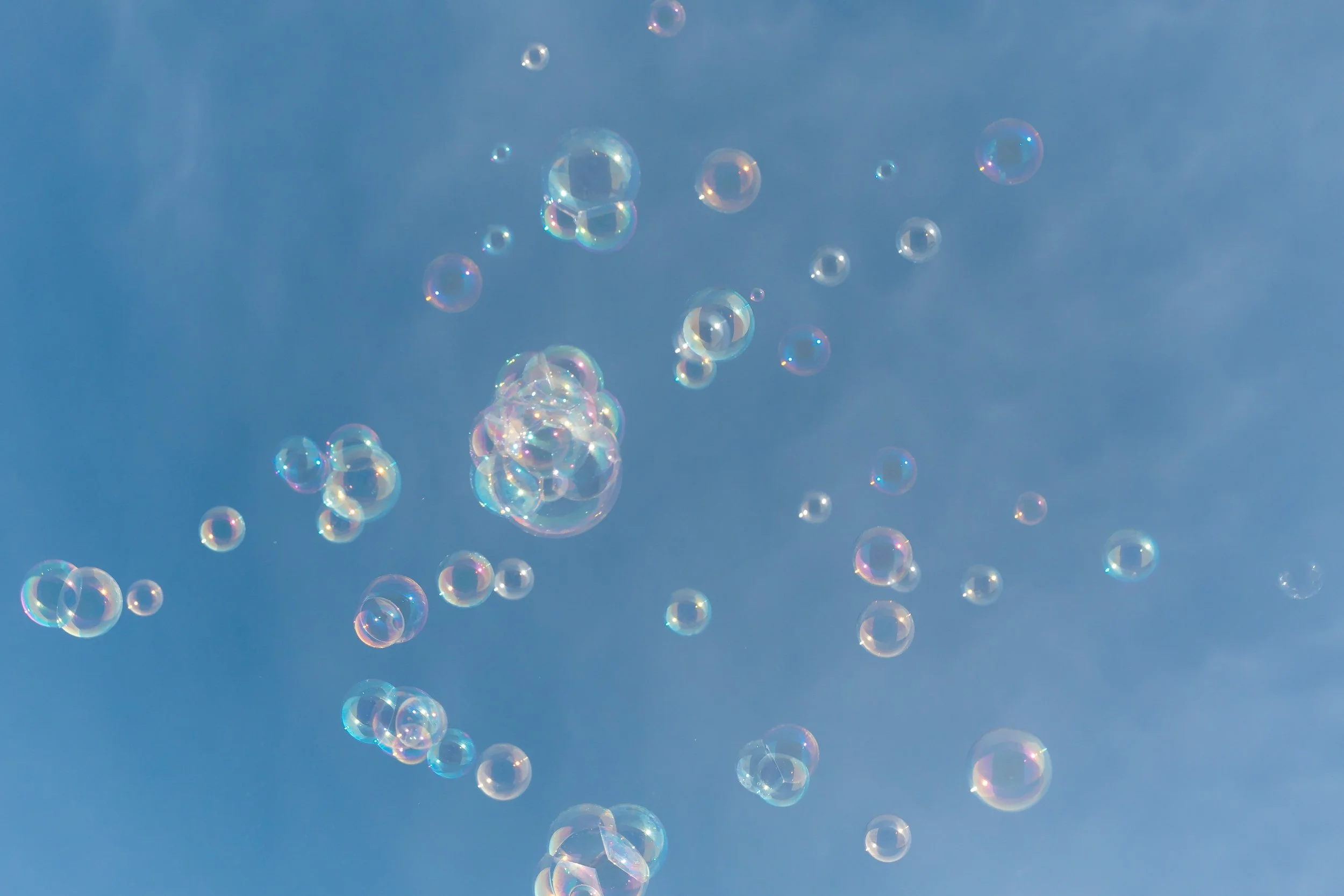 Soapy bubbles floating in the sky over a clear blue background.