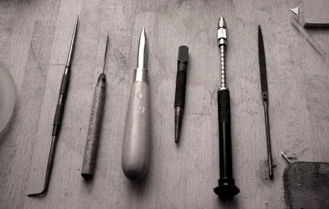 A collection of six precision screwdrivers with different sizes and shapes, laid out on a wooden surface.