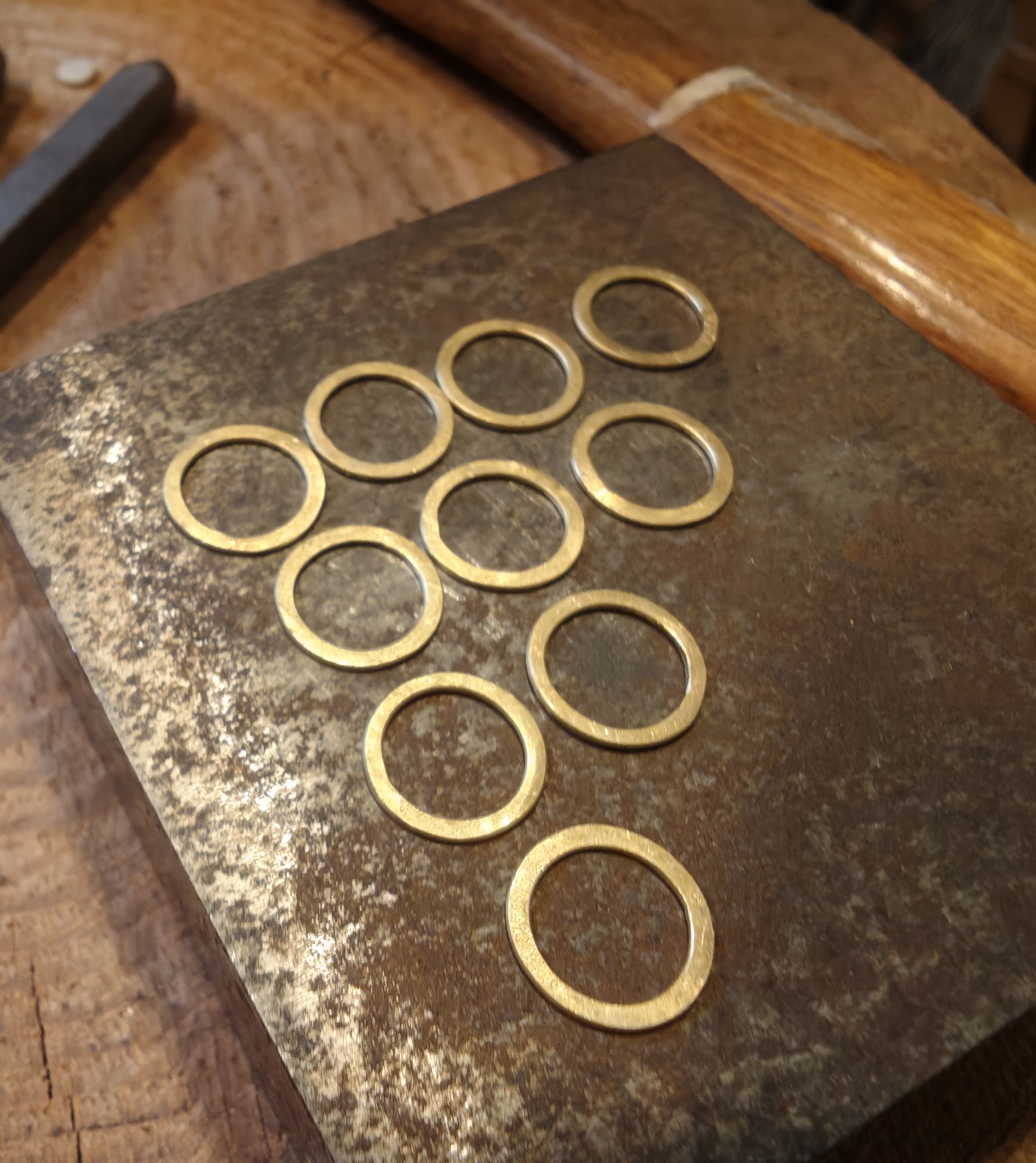 Close-up of a group of 18ct Yellow gold hammered circles sitting on a steel block.