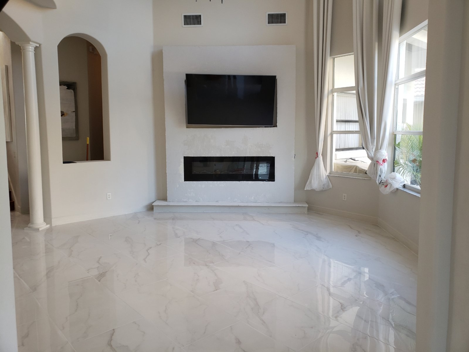 Living room remodel featuring a modern fireplace with wall-mounted TV and large-format polished tile flooring