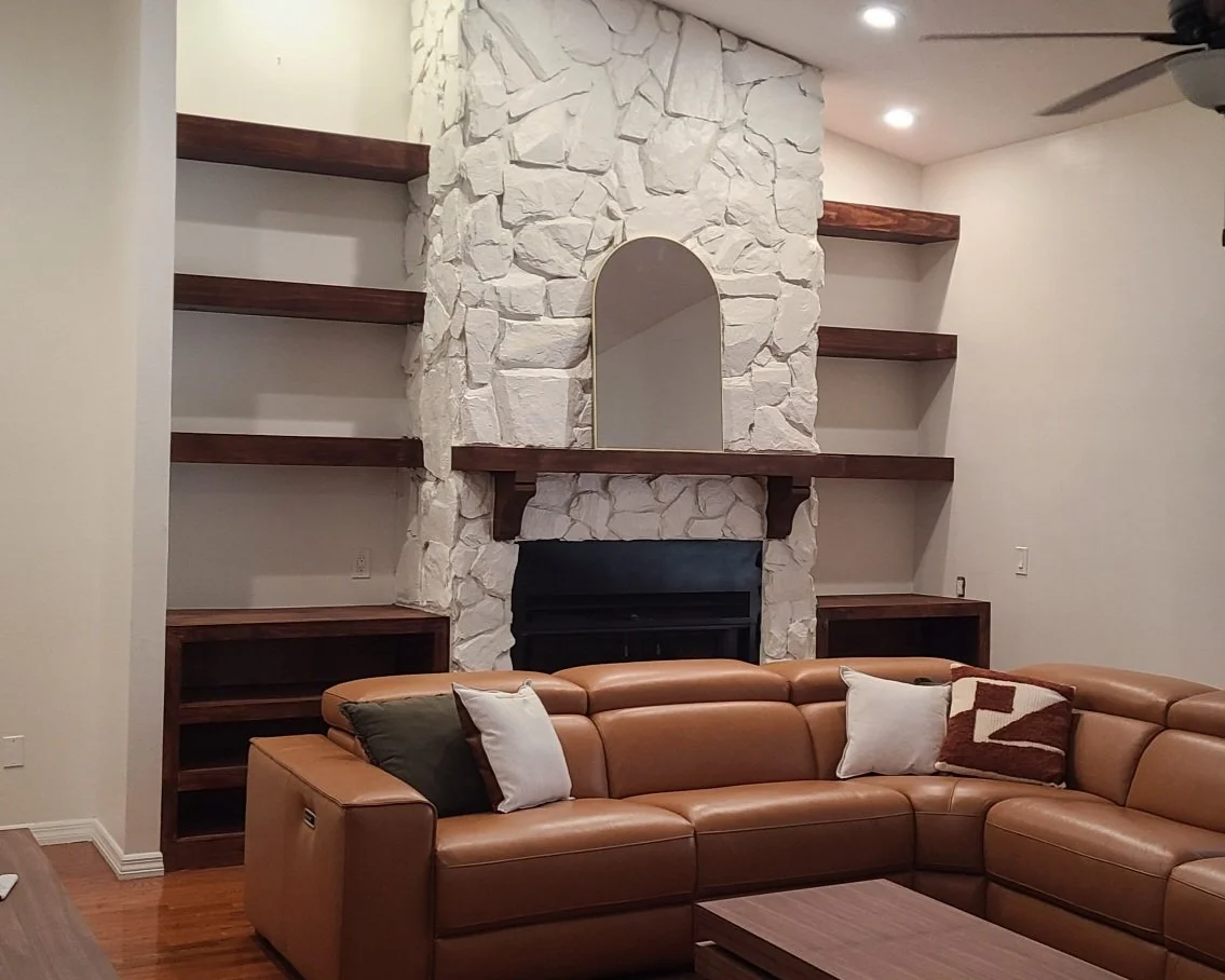 custom living room remodel featuring a stone fireplace with built-in wood shelving