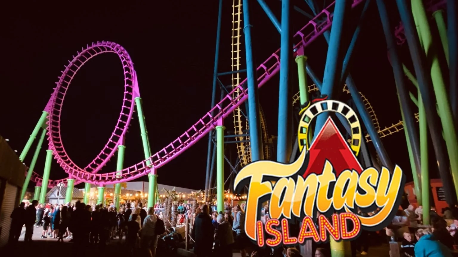 Night scene of a carnival at Fantasy Island featuring a roller coaster with pink tracks and green supports, and a crowd of people gathered at the base. The carnival is illuminated with bright lights.