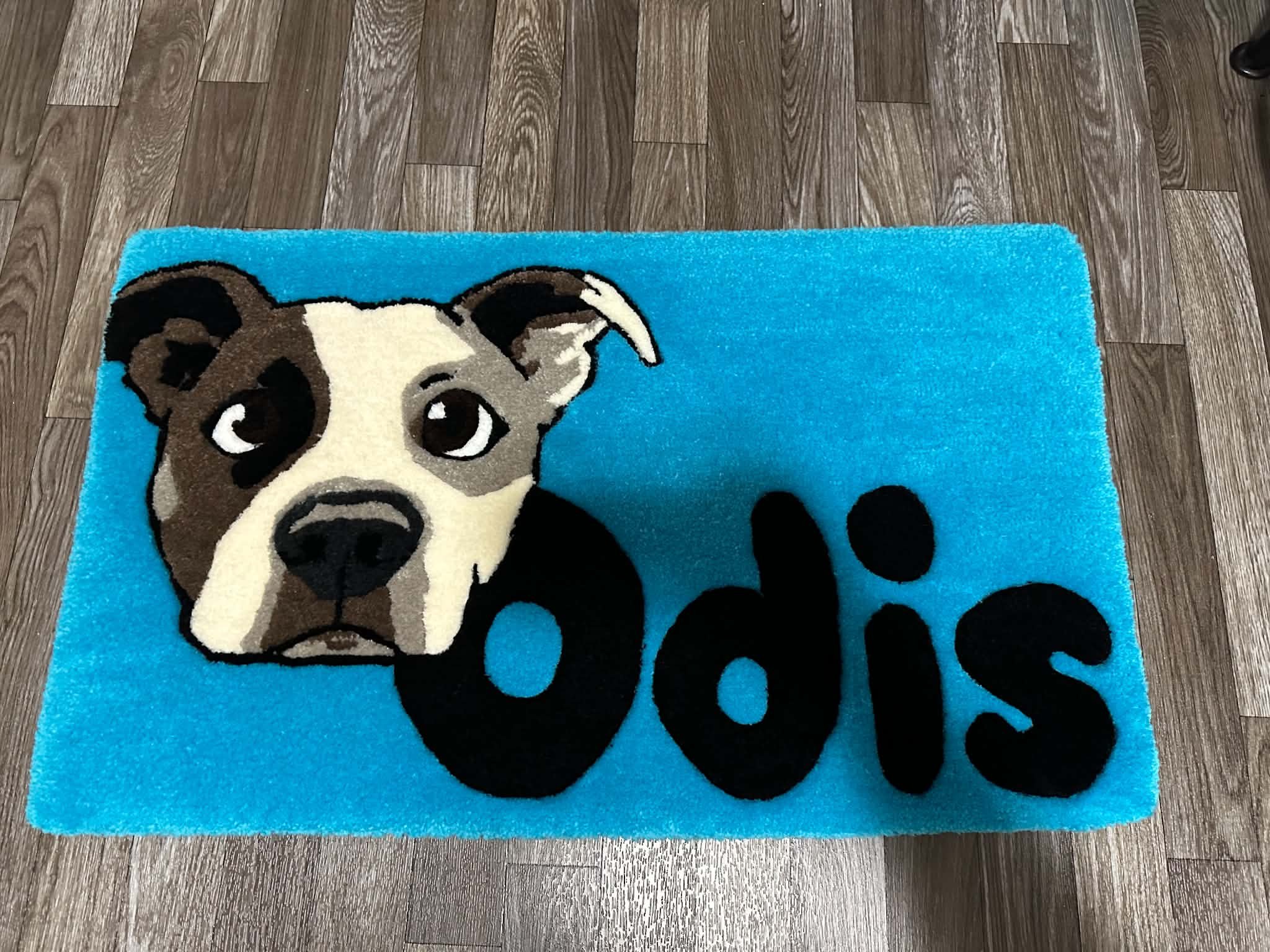 A blue rug with a cartoon dog face design on a wooden floor.