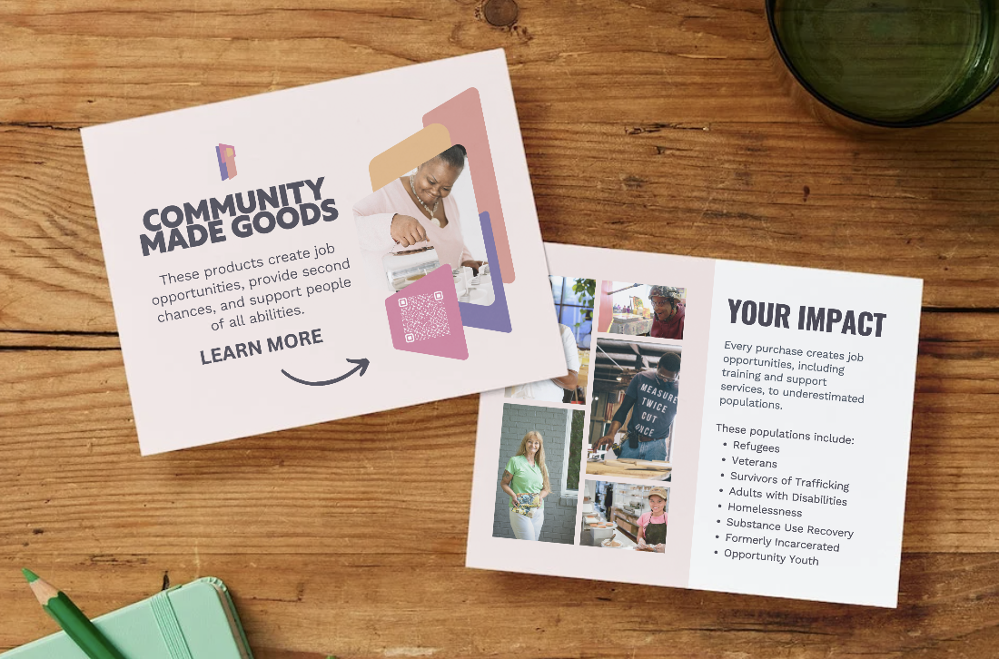 Brochure about community-made goods with images of diverse individuals working and smiling, and text highlighting job creation and impact on underserved populations, laid on a wooden table with a green notebook and pen nearby.
