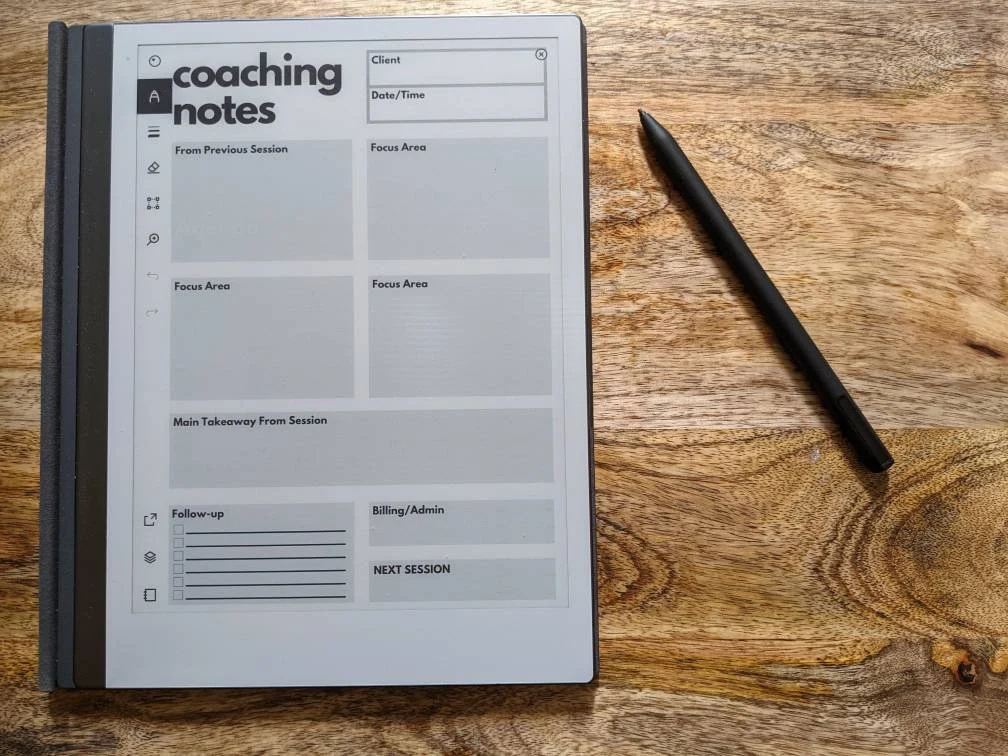 A digital coaching notes template on a tablet with a black stylus to the right, placed on a wooden surface.
