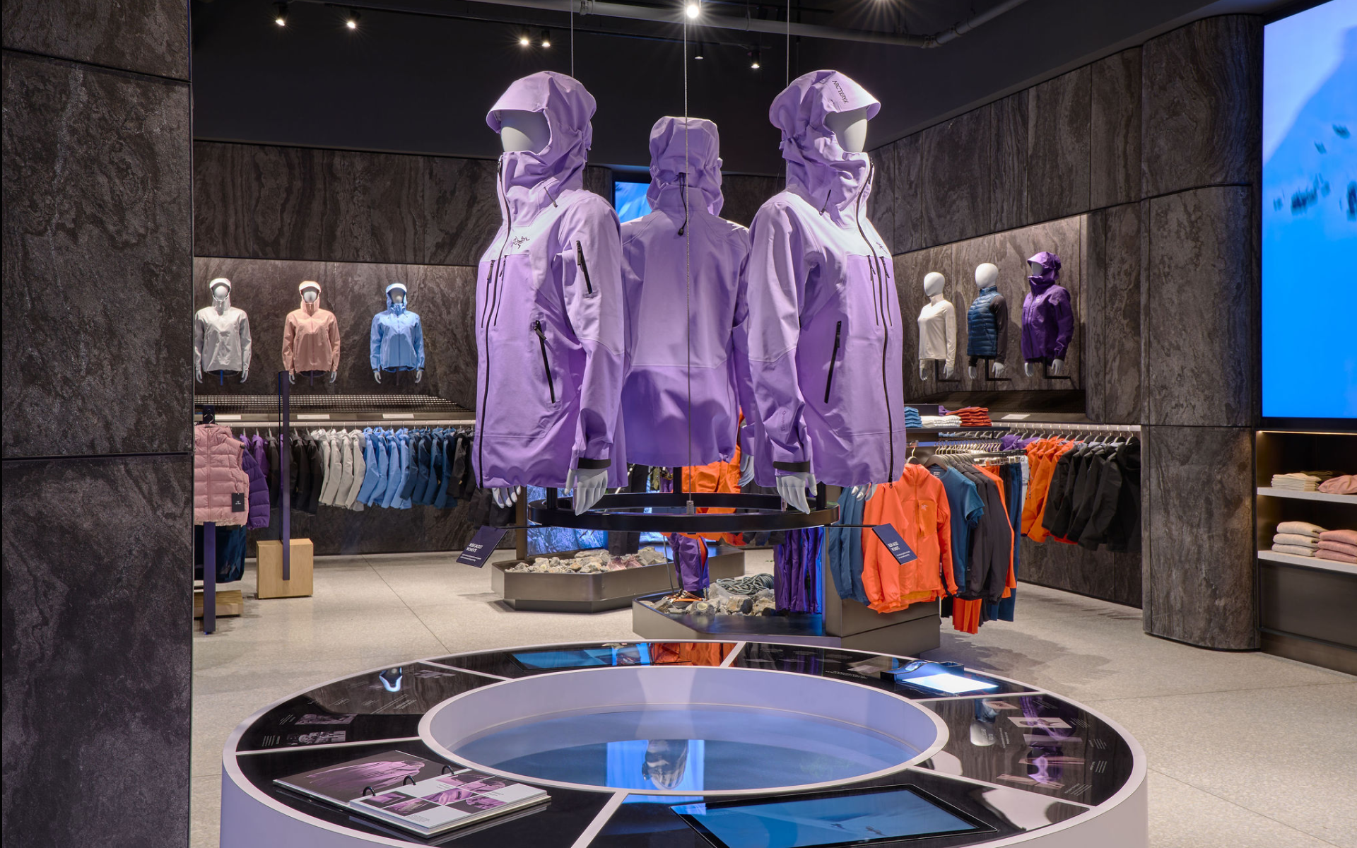 Store display of purple jackets on mannequins, surrounded by other colorful jackets and clothing items arranged on shelves and racks.