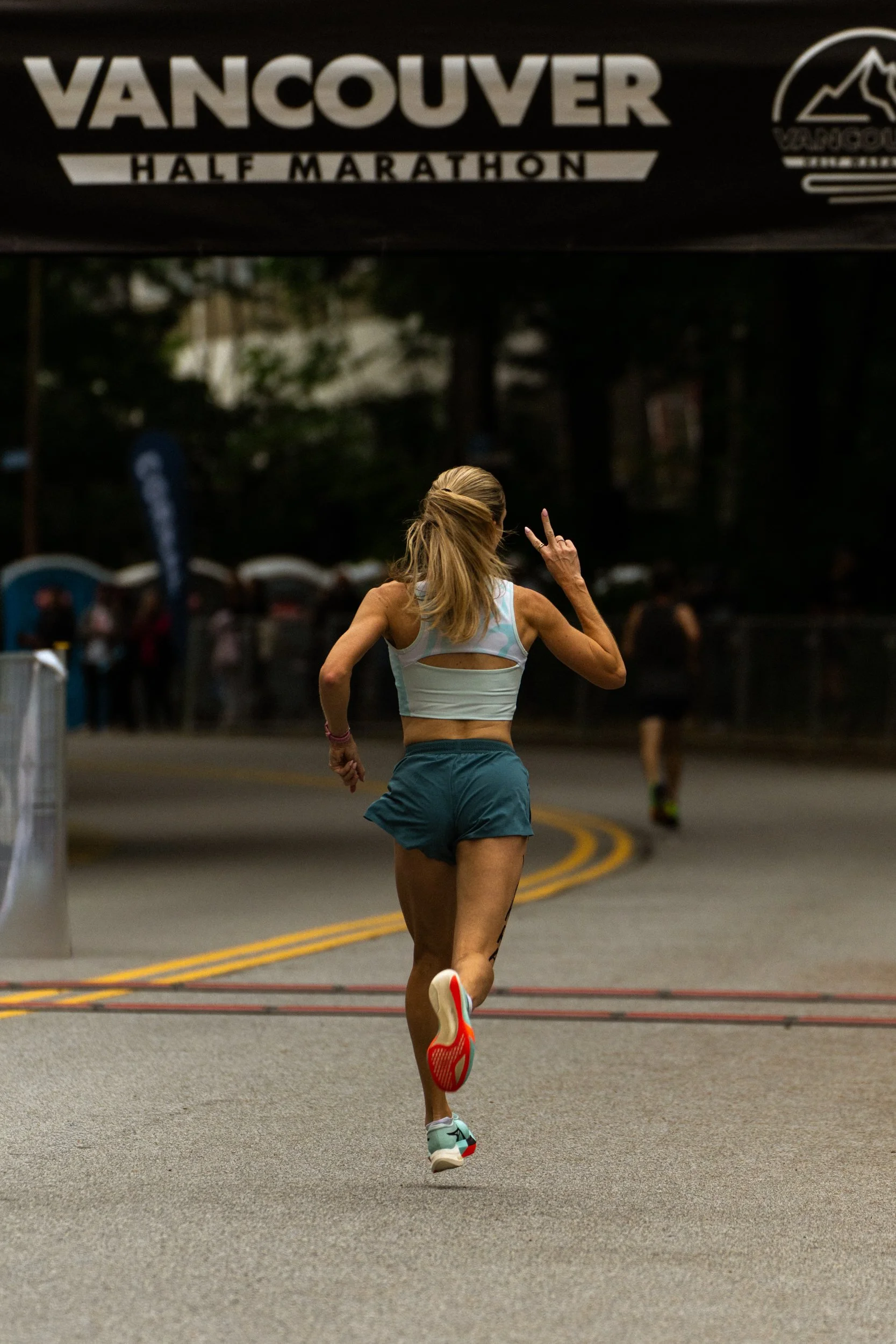 A woman running in a half marathon under the Vancouver event banner.