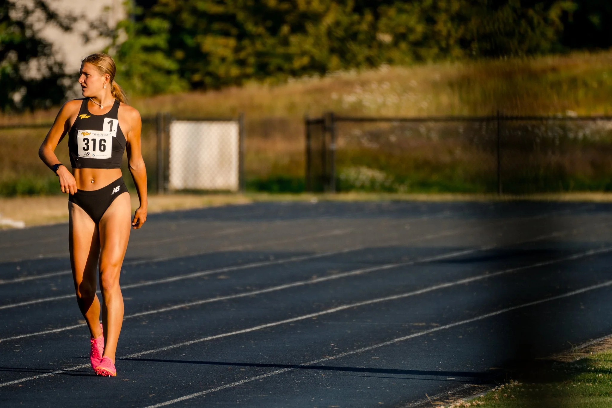 A female athlete in black athletic wear with a race bib number 316, walking on a track during a race or training session.