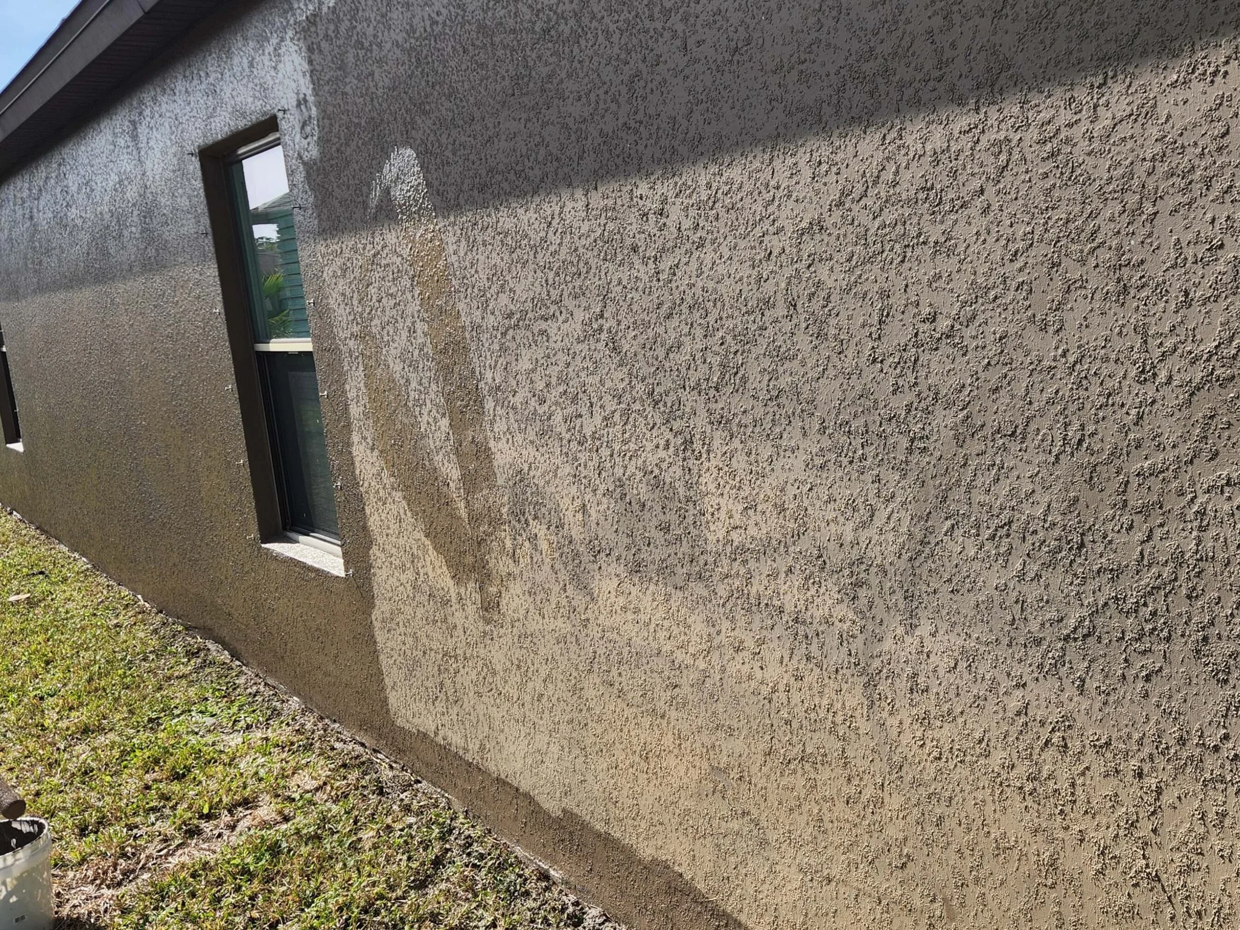 Exterior house painting on stucco wall with fresh paint application in Brevard County Florida