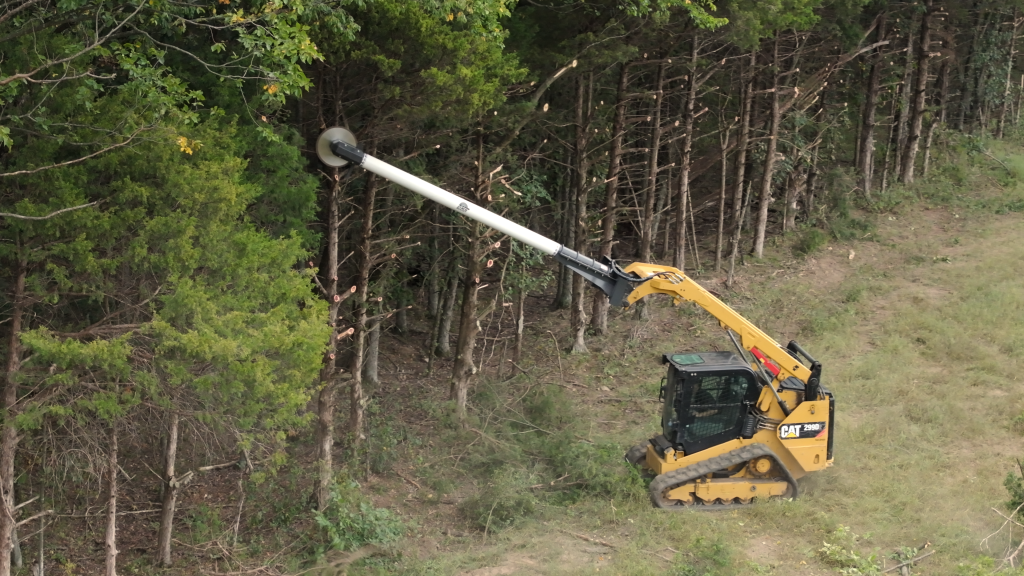 Cutting back overhanging tree limbs along farmland and pasture fencing
